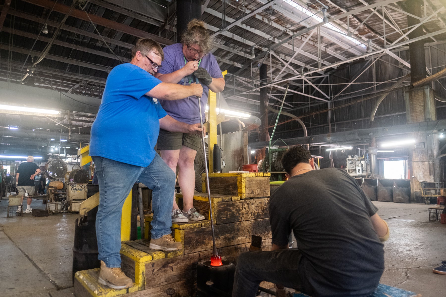 Three peoplr working together on a task in an industrial setting