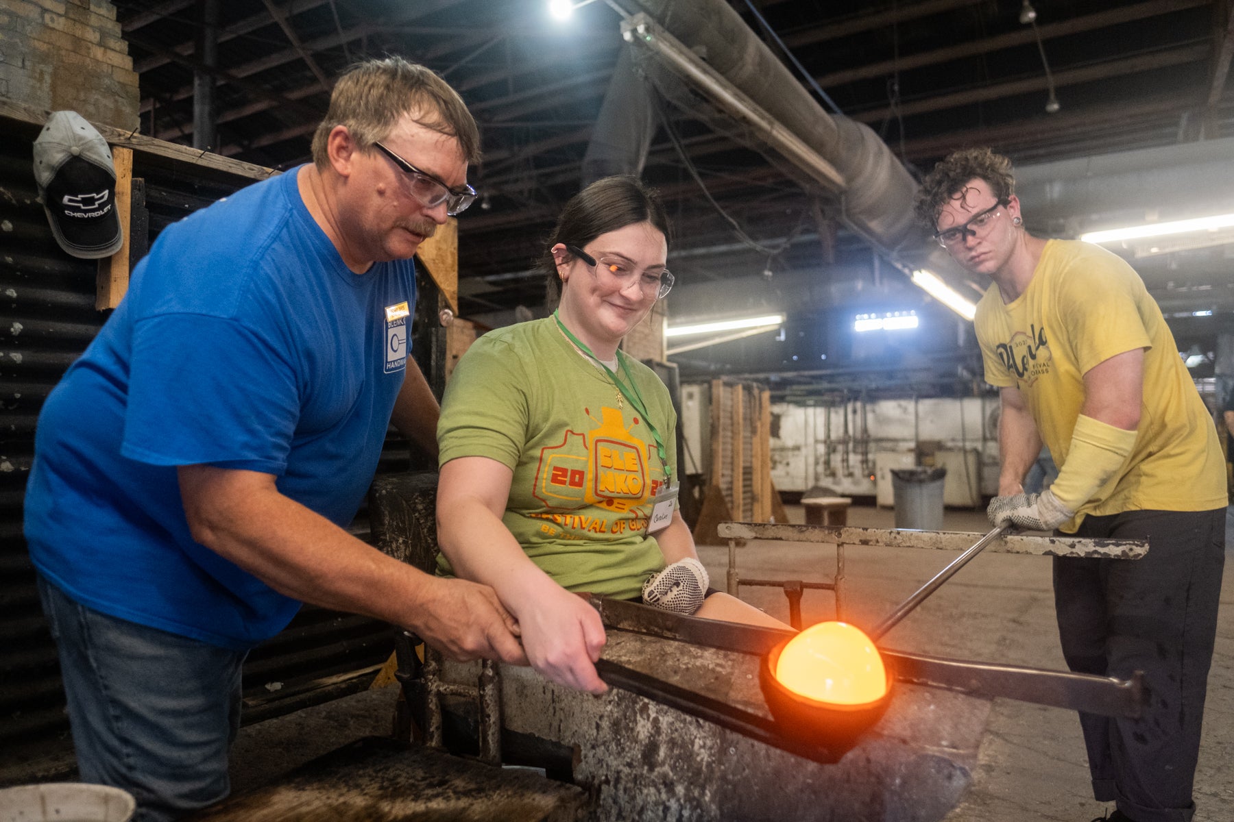 Three people working with hot metal in a workshop setting
