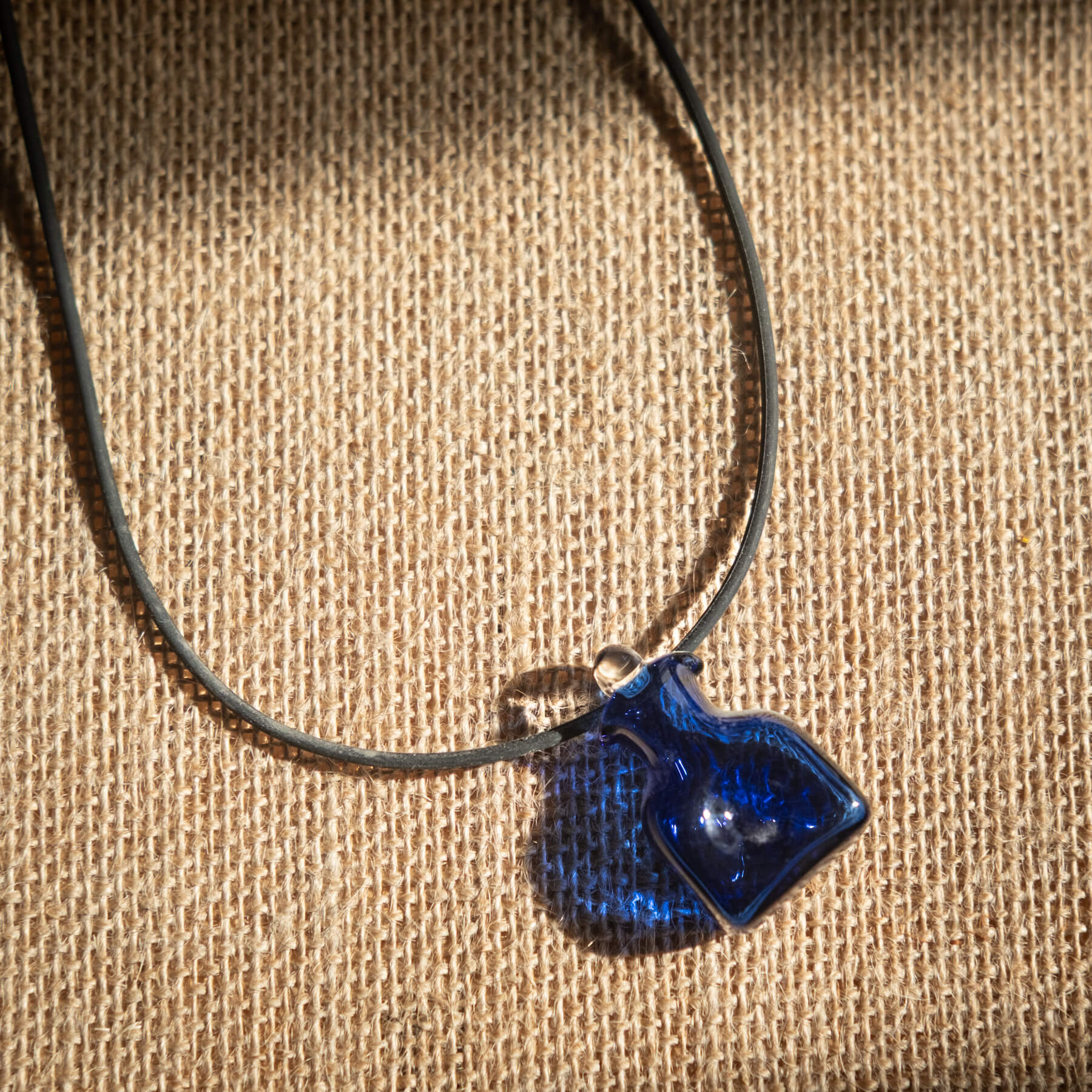 Necklace with a blue pendant on a textured beige background