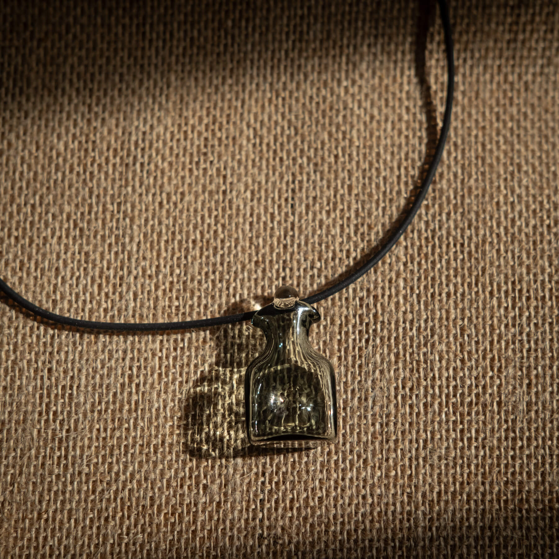Necklace with a bottle pendant on a brown textured background