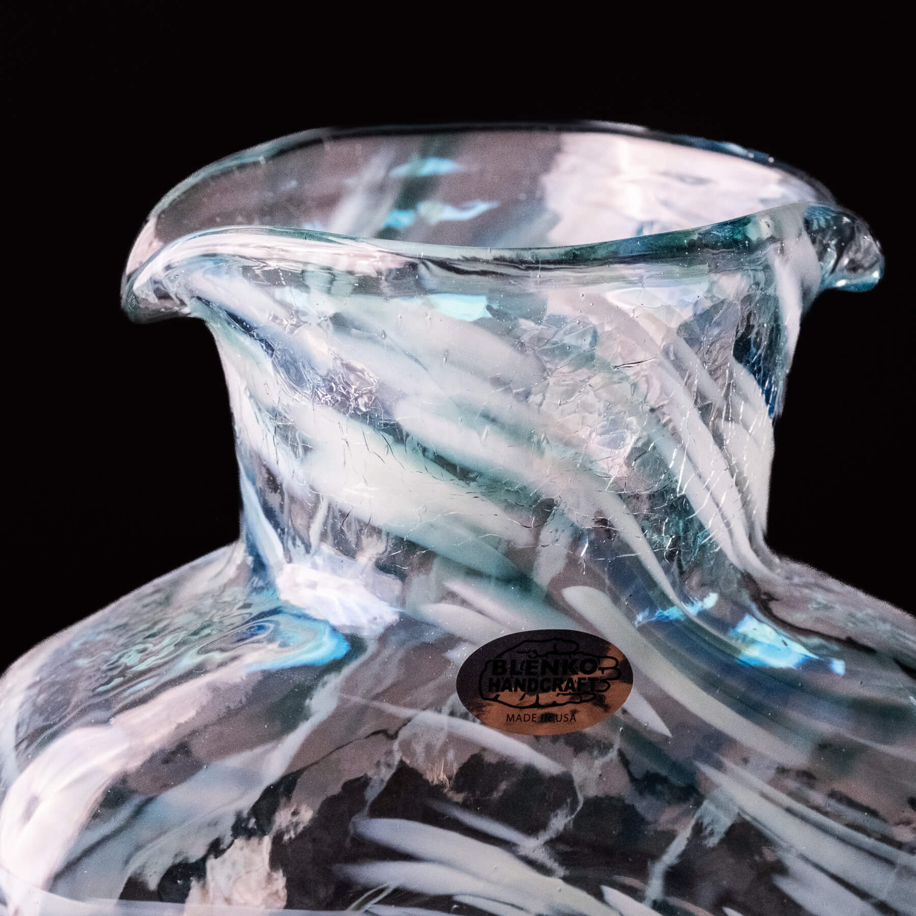 Glass vase with artistic design and a visible brand label on a black background
