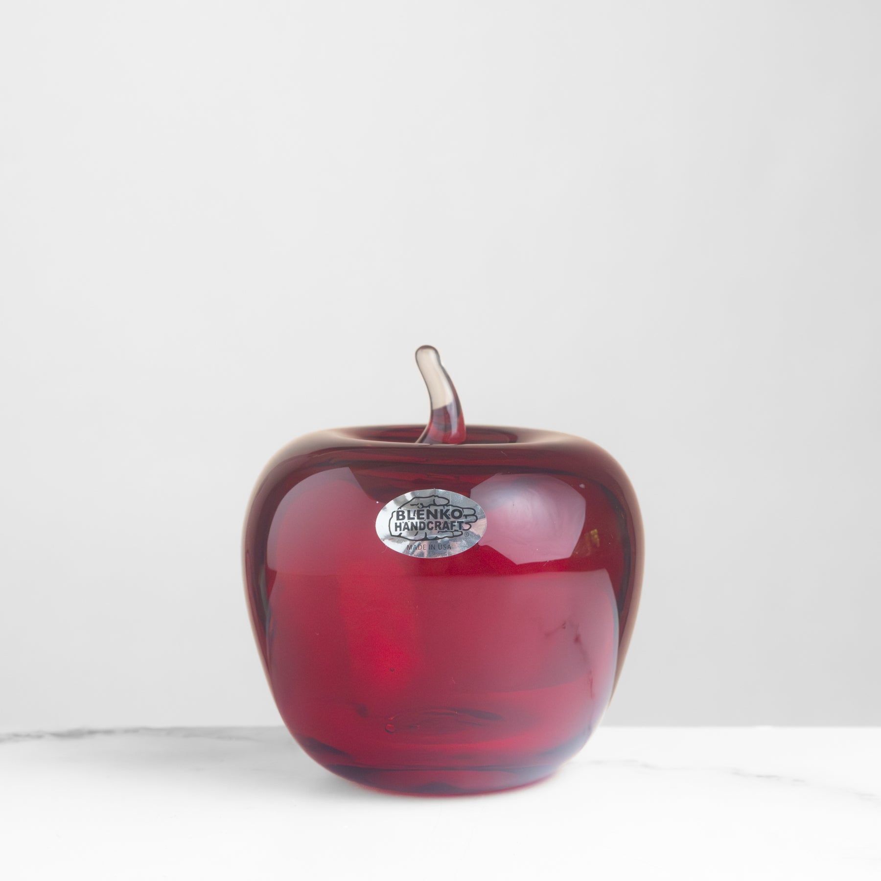 Red glass apple with a silver label on a white background