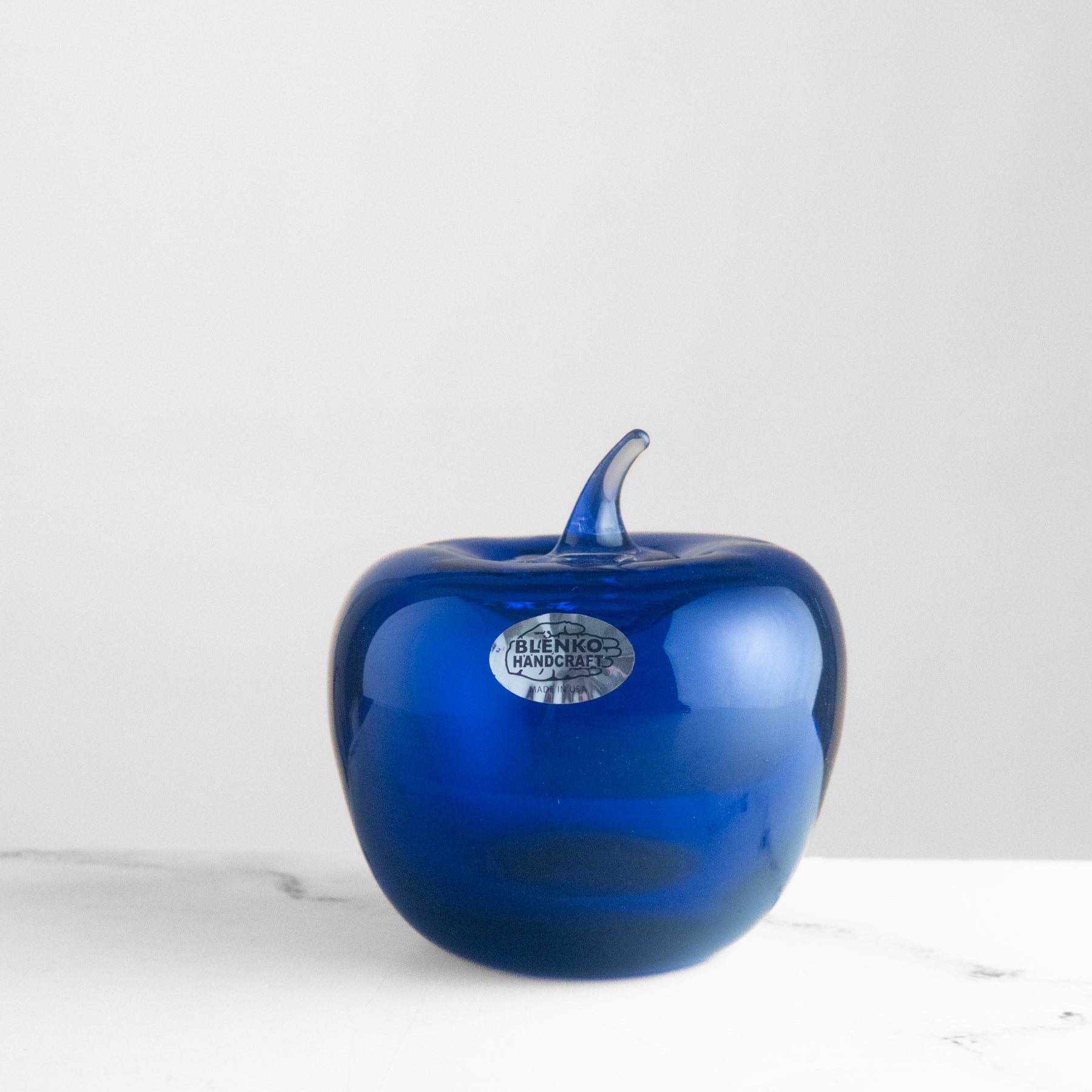 Blue glass apple with a brand label on a white background