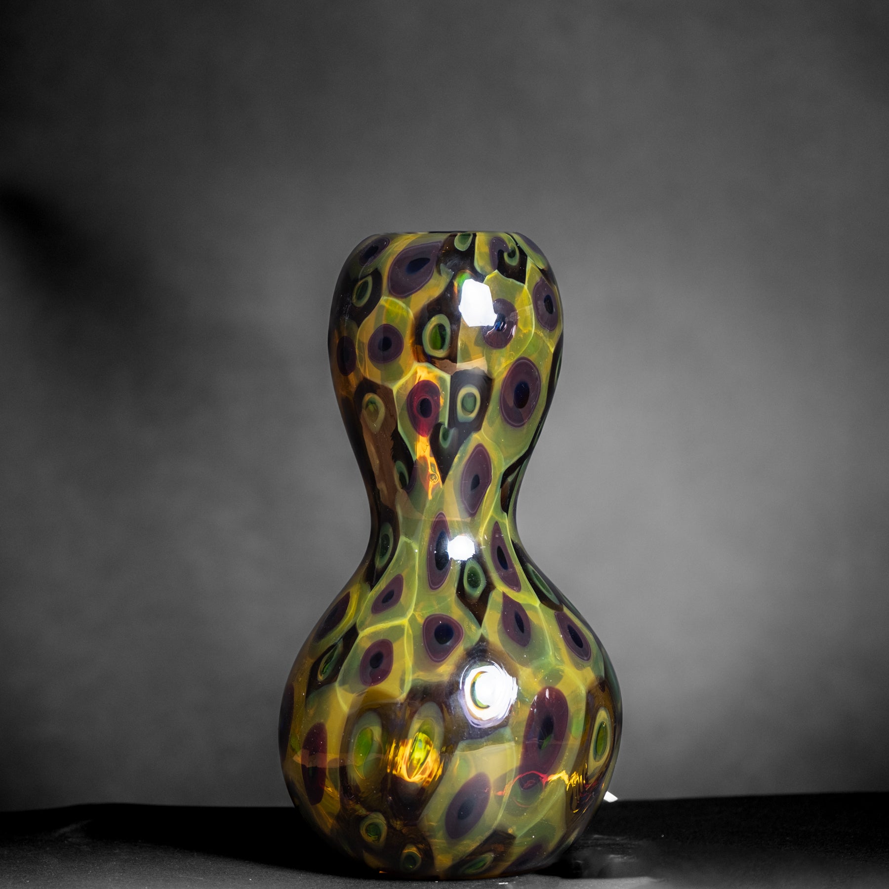 Decorative glass vase with colorful pattern on a dark background