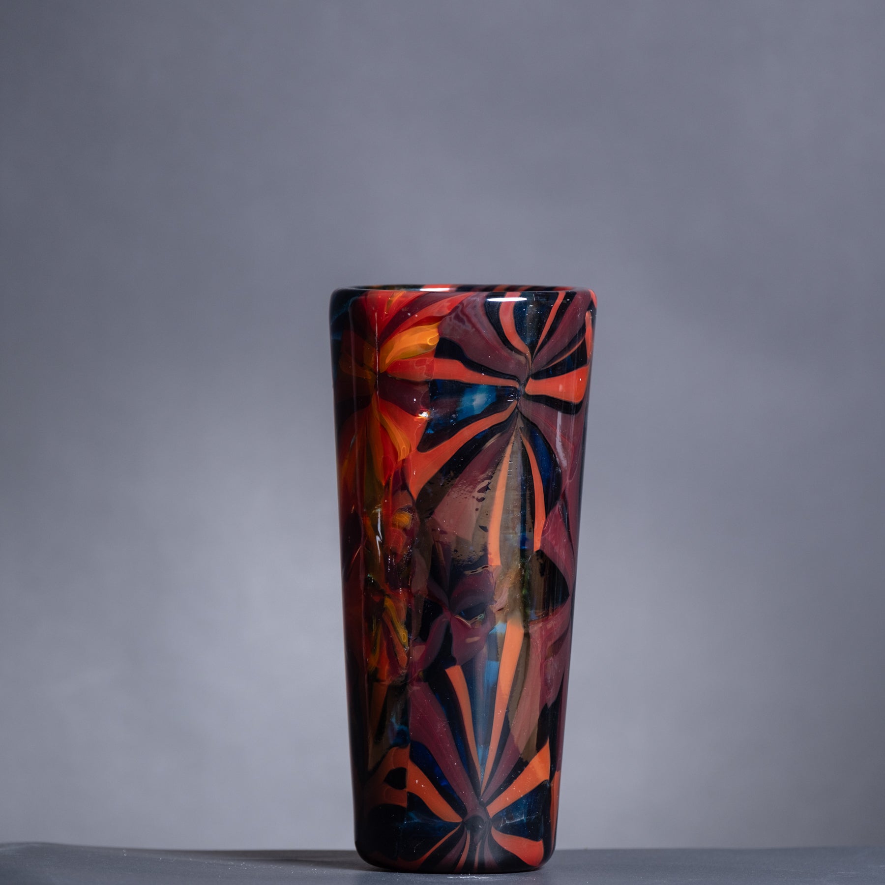 Colorful glass vase with abstract design on a gray background