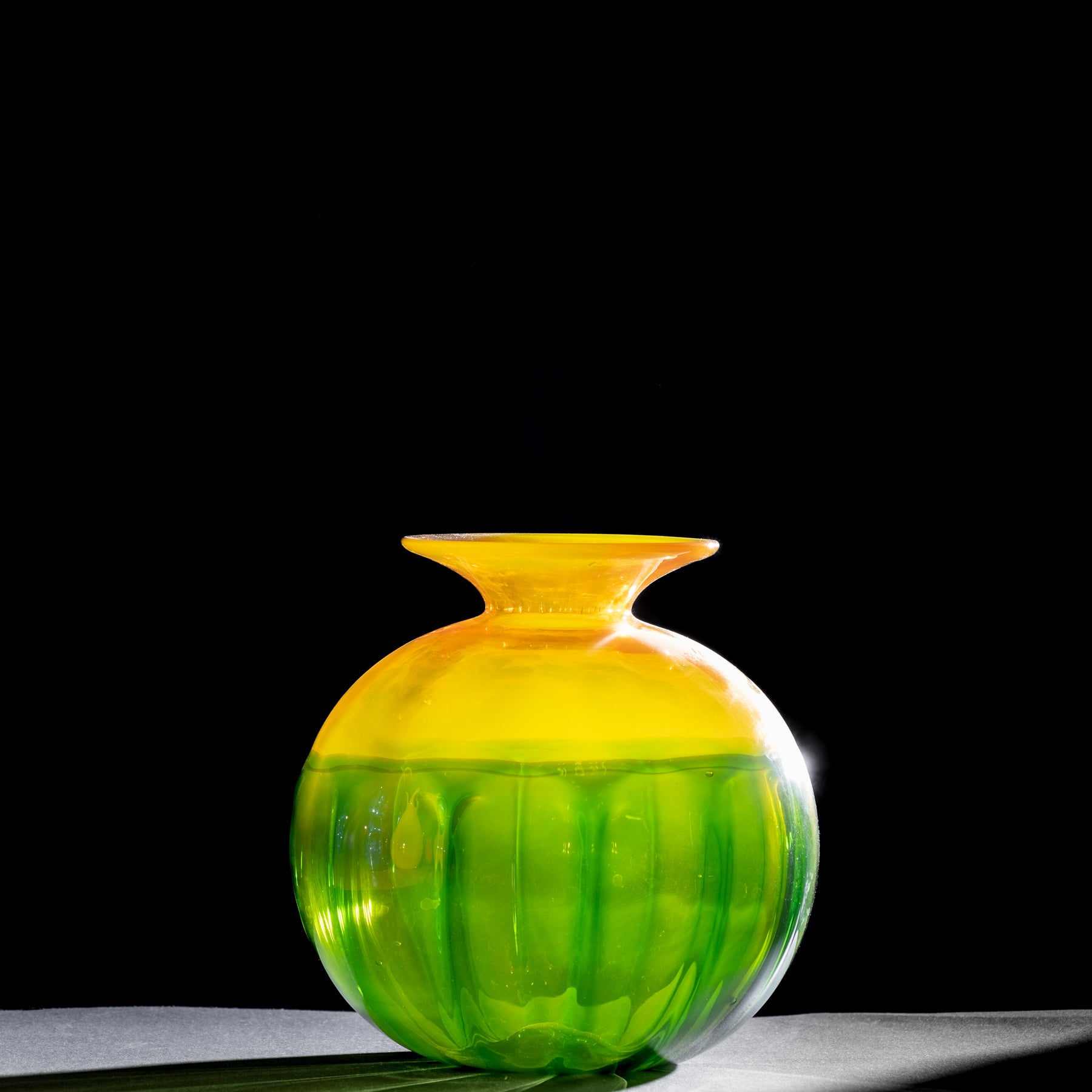 Glass vase with yellow and green gradient on a black background