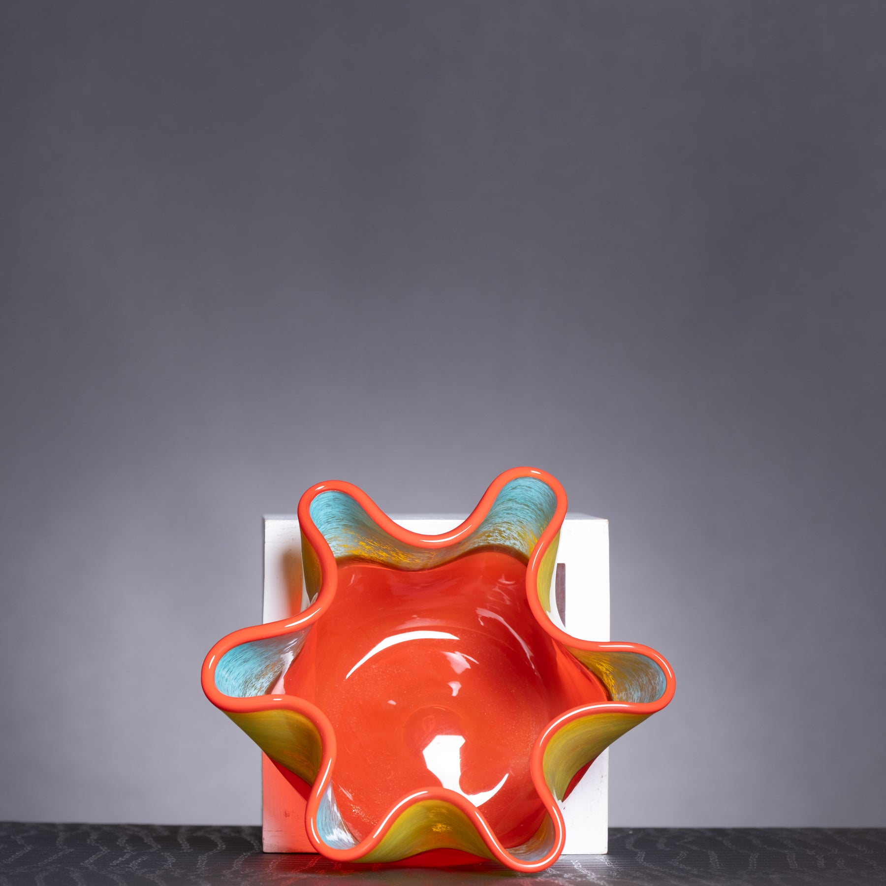 Decorative bowl with wavy design in red, yellow, and blue on a dark gray background