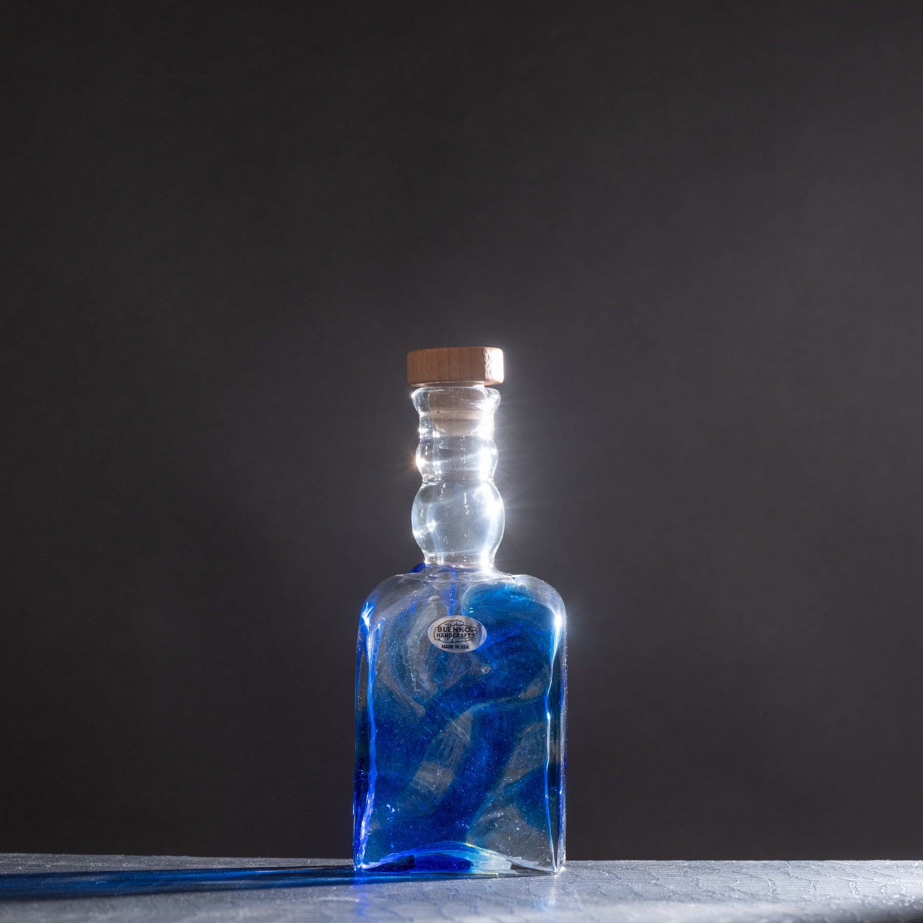 Blue glass bottle with cork on a dark background
