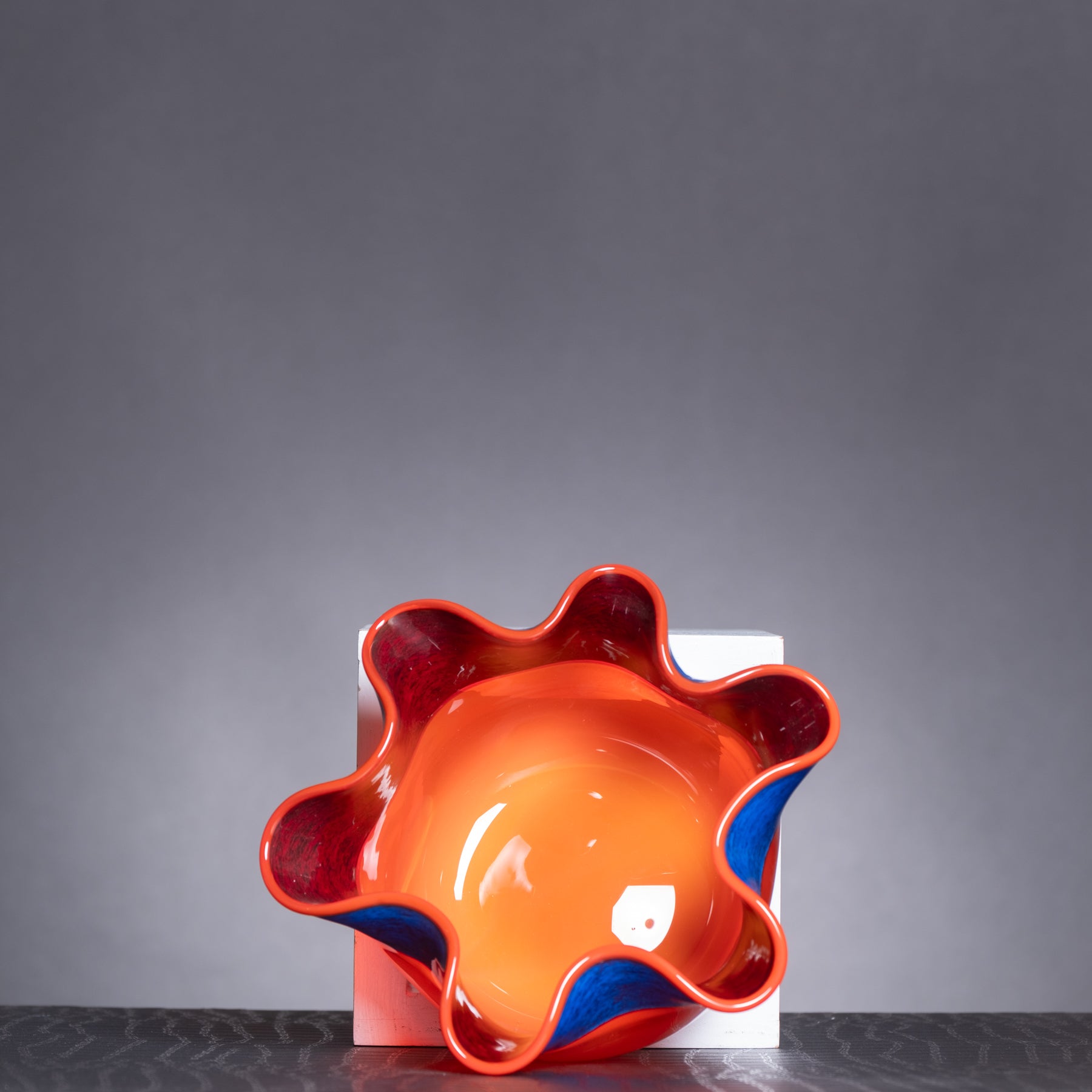 Ceramic bowl with wavy design in orange and red on a gray background