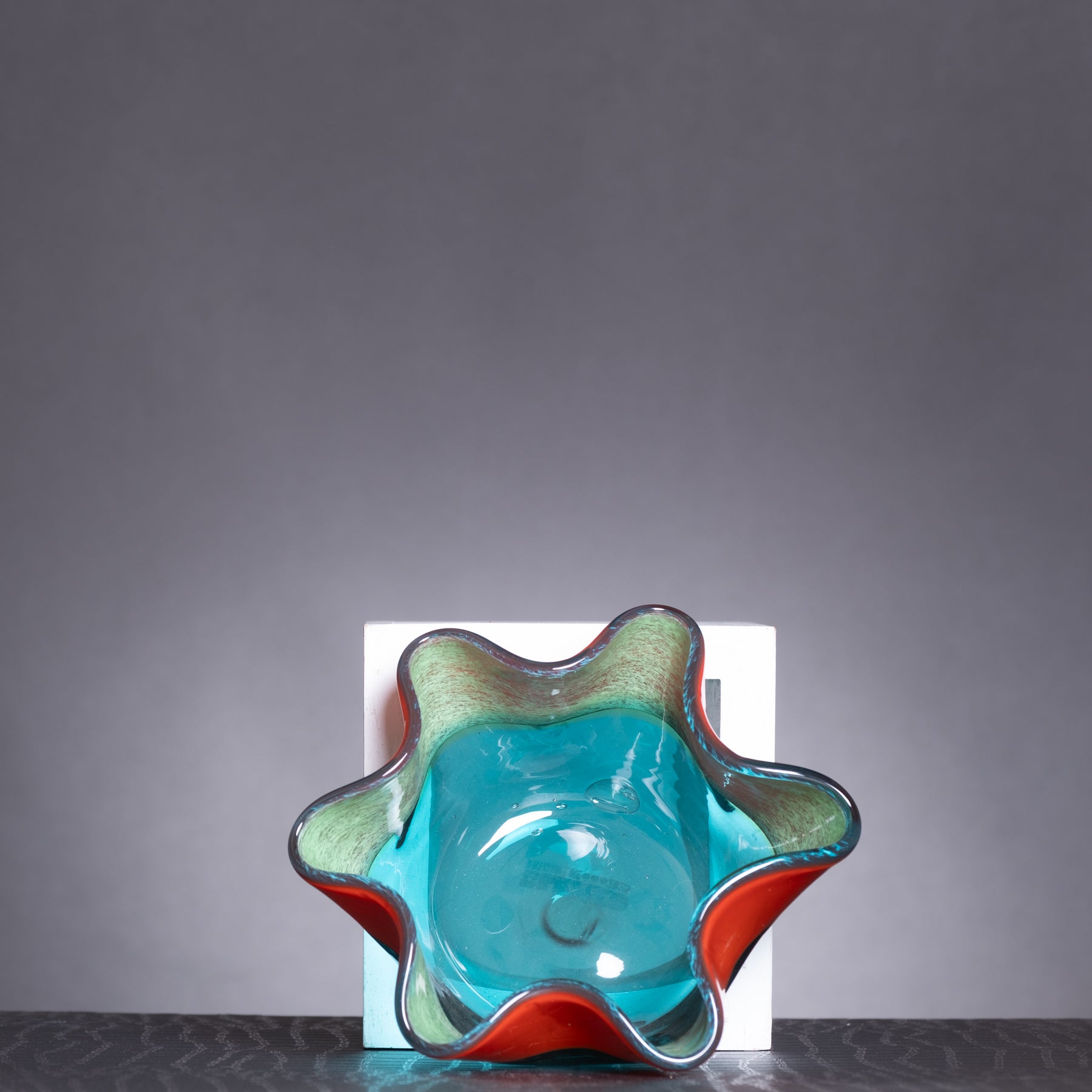 Colorful glass bowl with a textured surface on a gray background