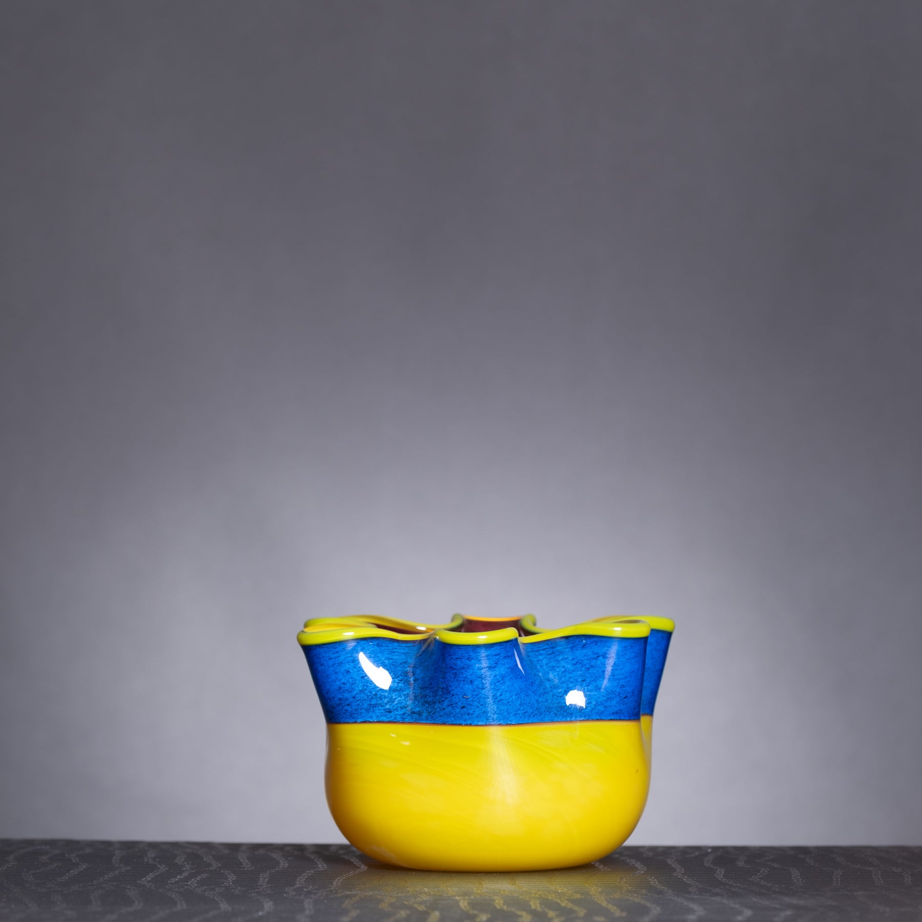 Yellow and blue ceramic bowl on a gray surface with a gray background