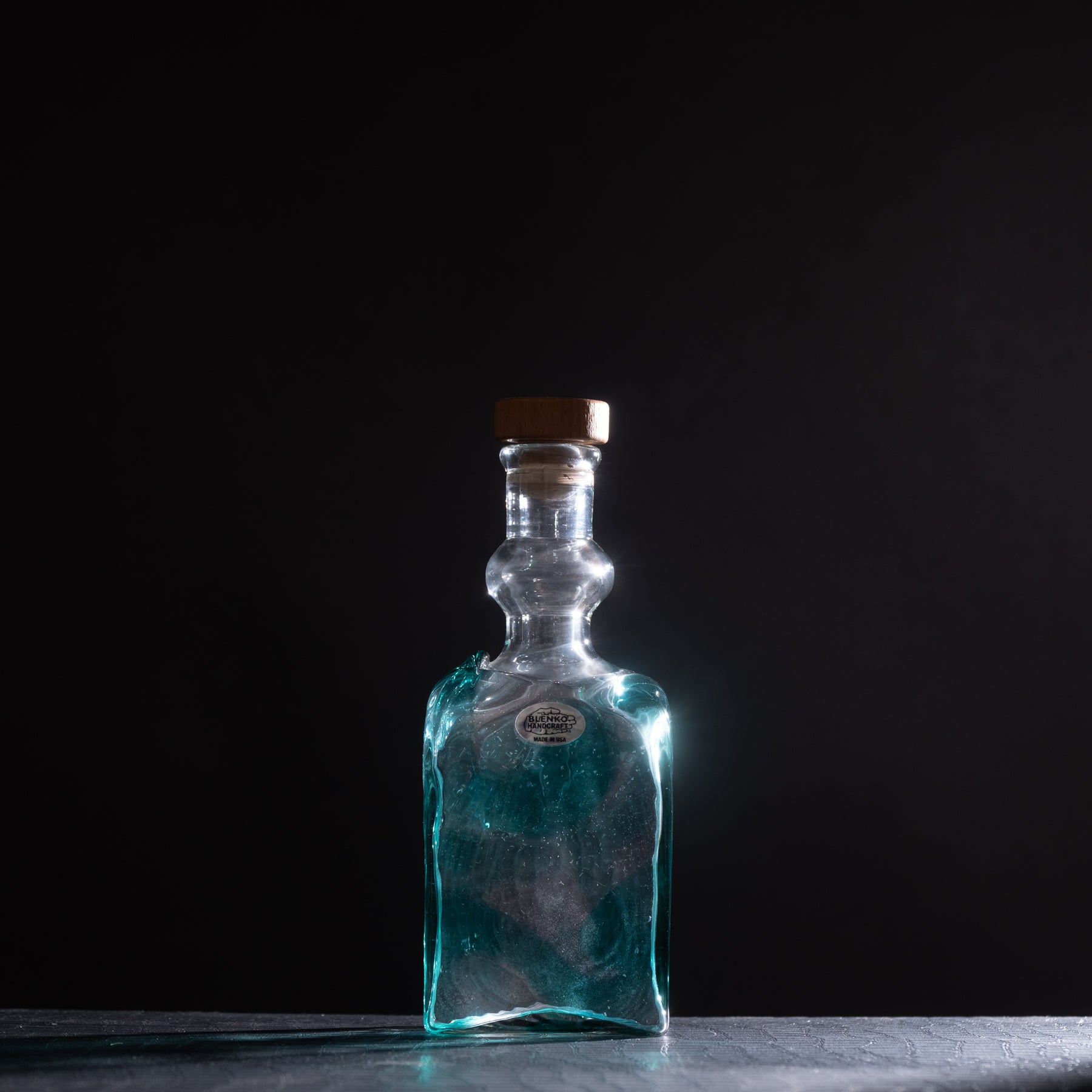 Clear glass bottle with a wooden cap on a dark background
