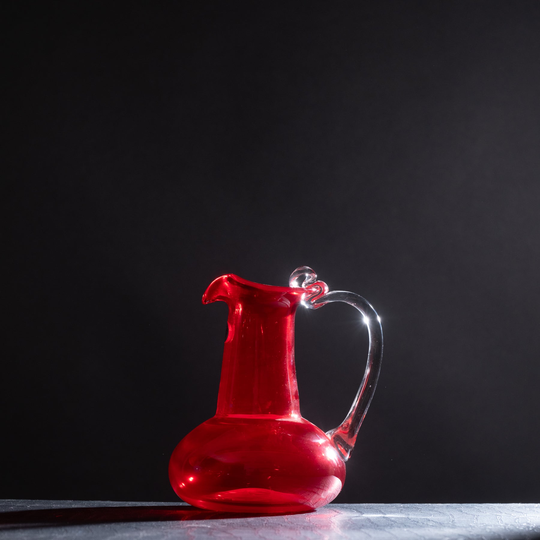 Red glass pitcher on a dark background