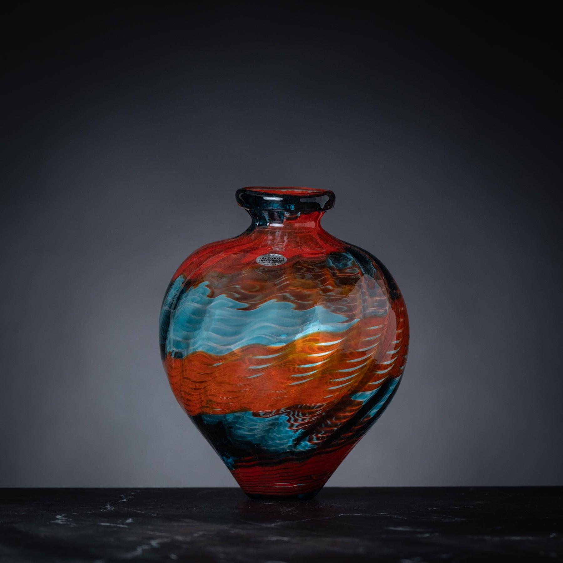 Colorful glass vase on a dark surface with a gray background