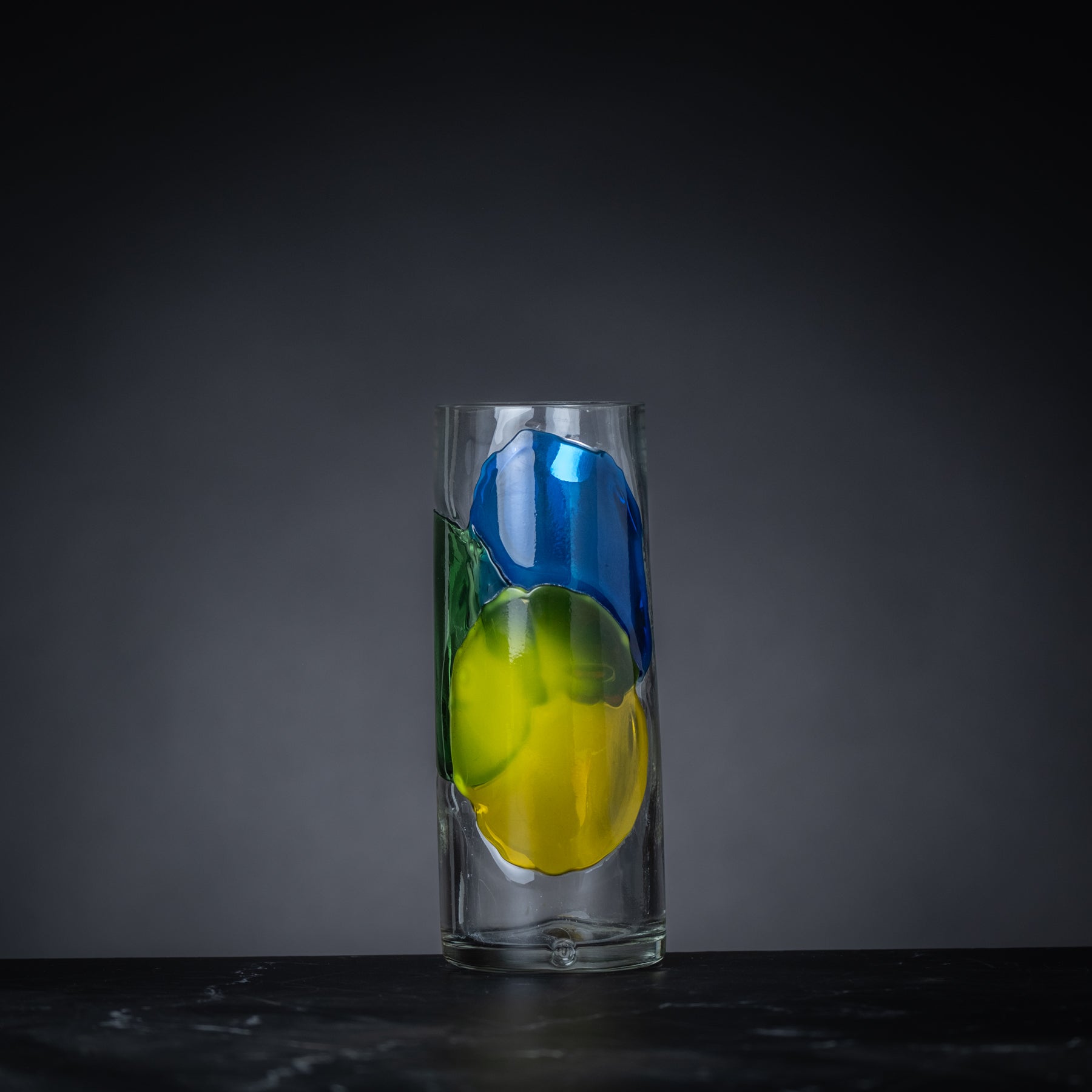 Glass vase with blue and green abstract design on a dark background