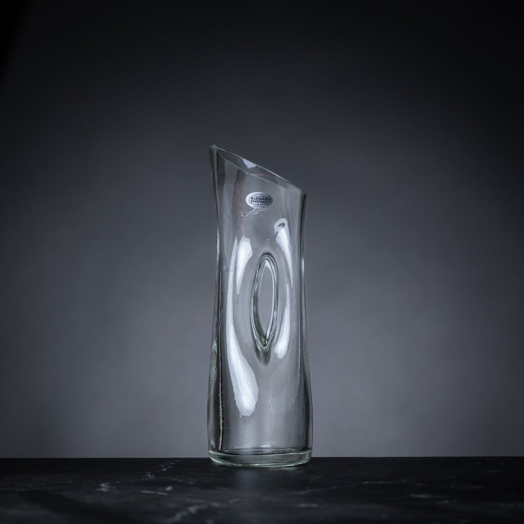 Clear glass vase on a dark surface with a gray background