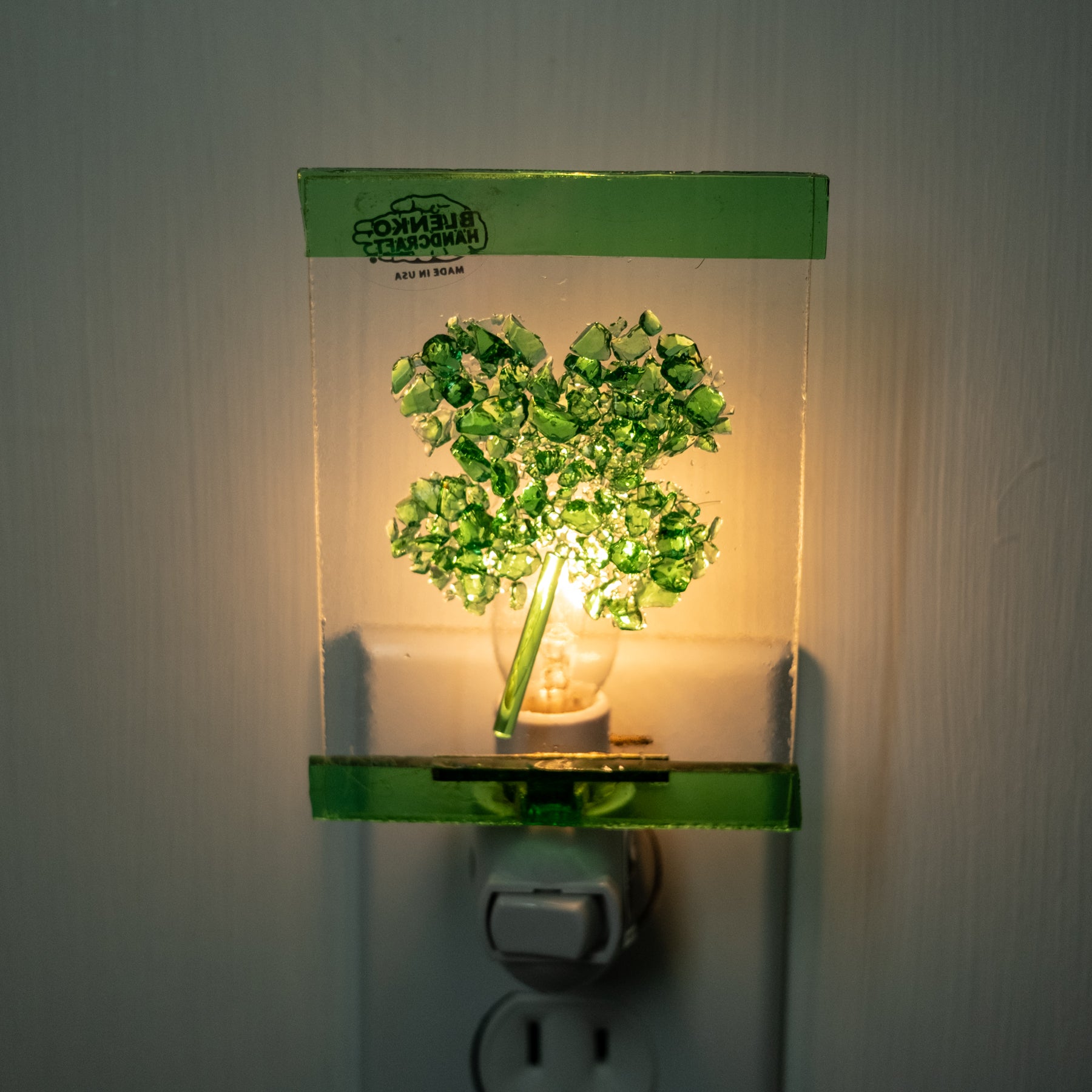 Green tree-shaped night light attached to a wall outlet.