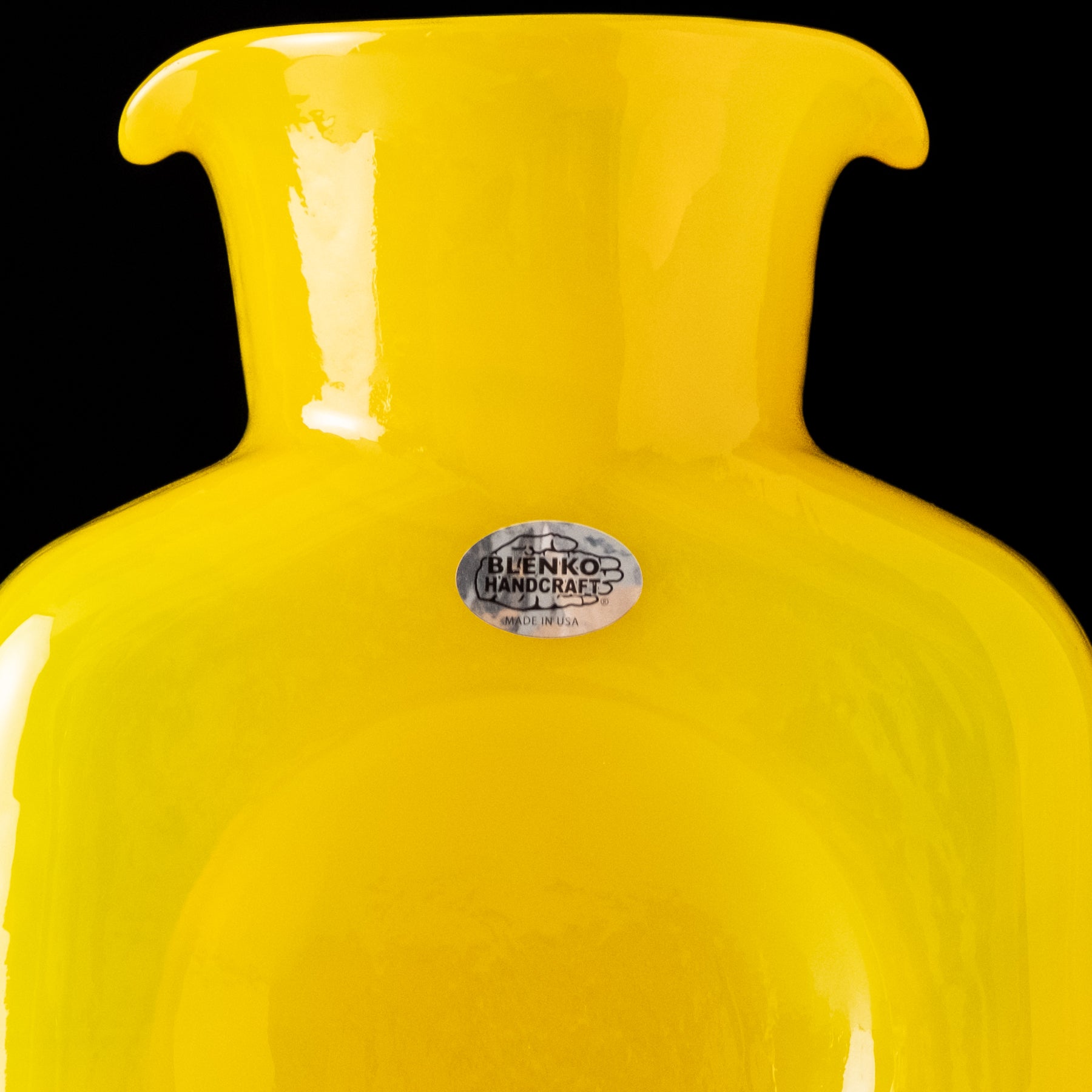 Yellow vase with a visible brand label on a black background