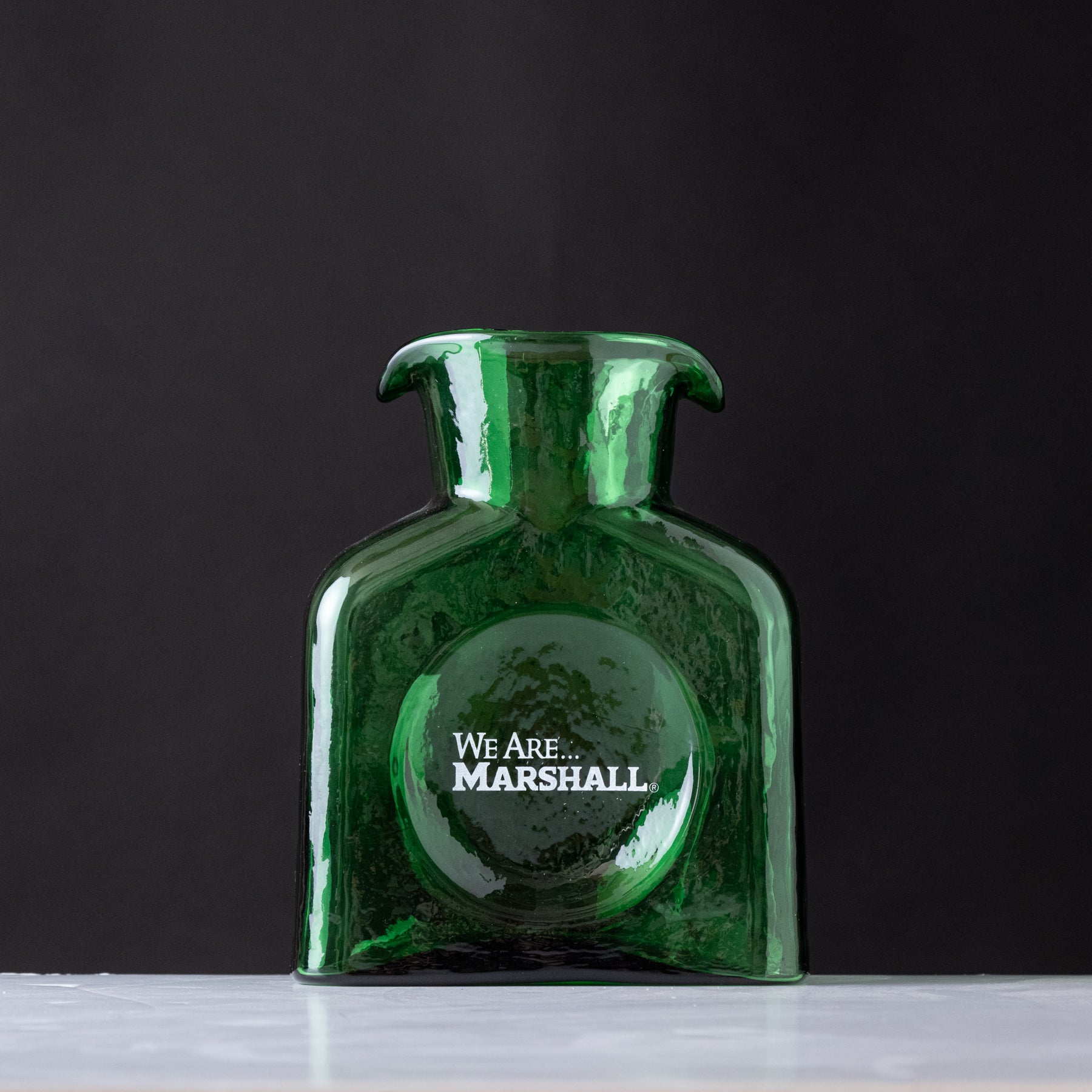 Green bottle with 'We Are Marshall' logo on a dark background
