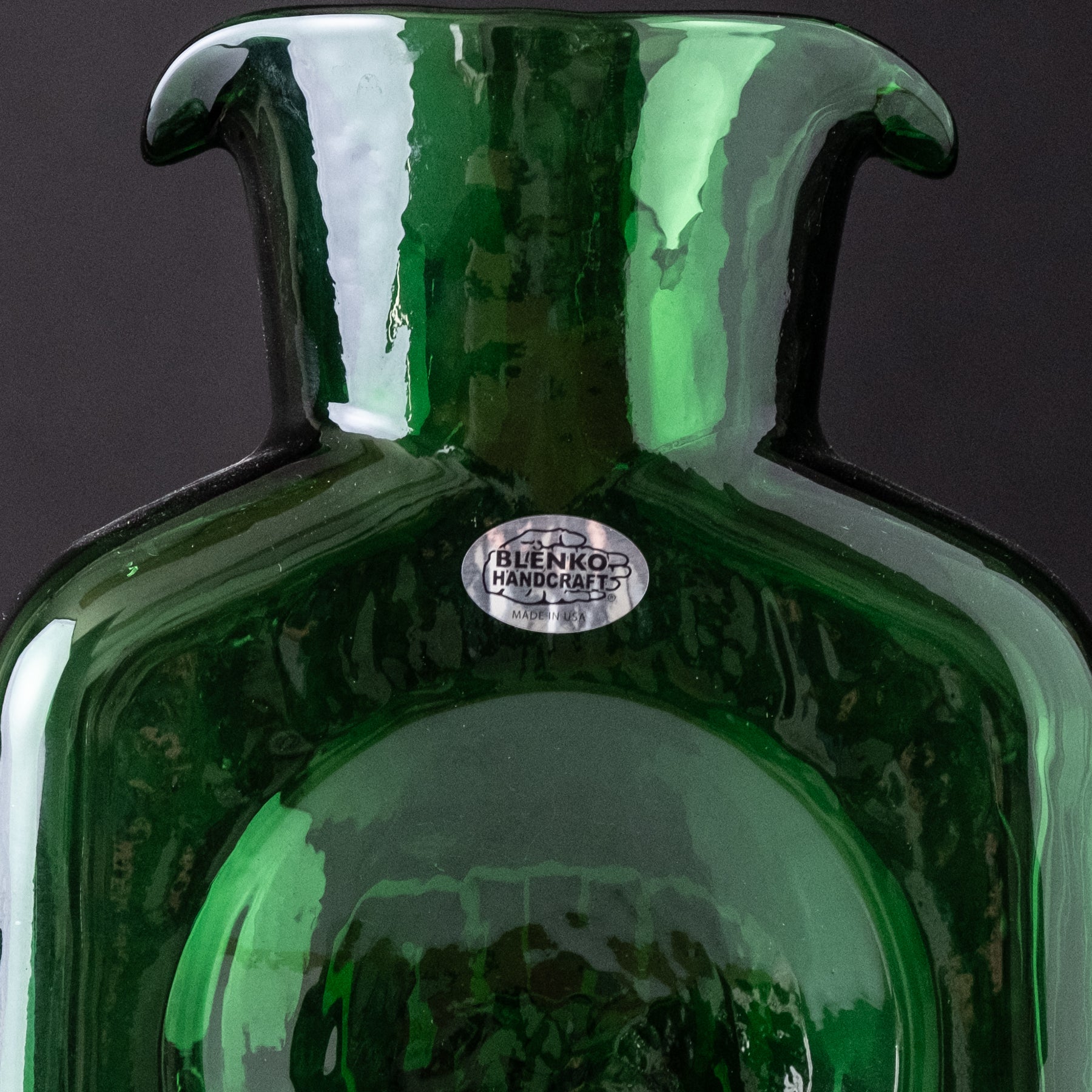 Close-up of a green glass bottle with a visible brand label on a dark background