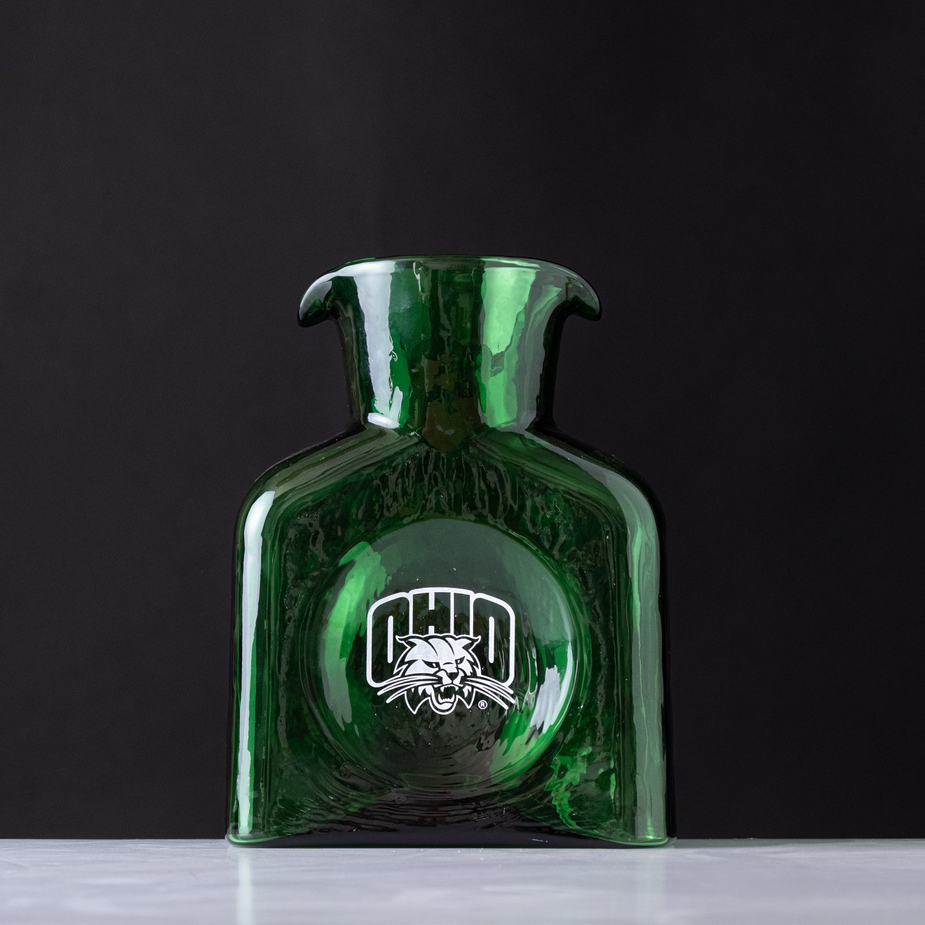 Green glass bottle with a logo on a black background