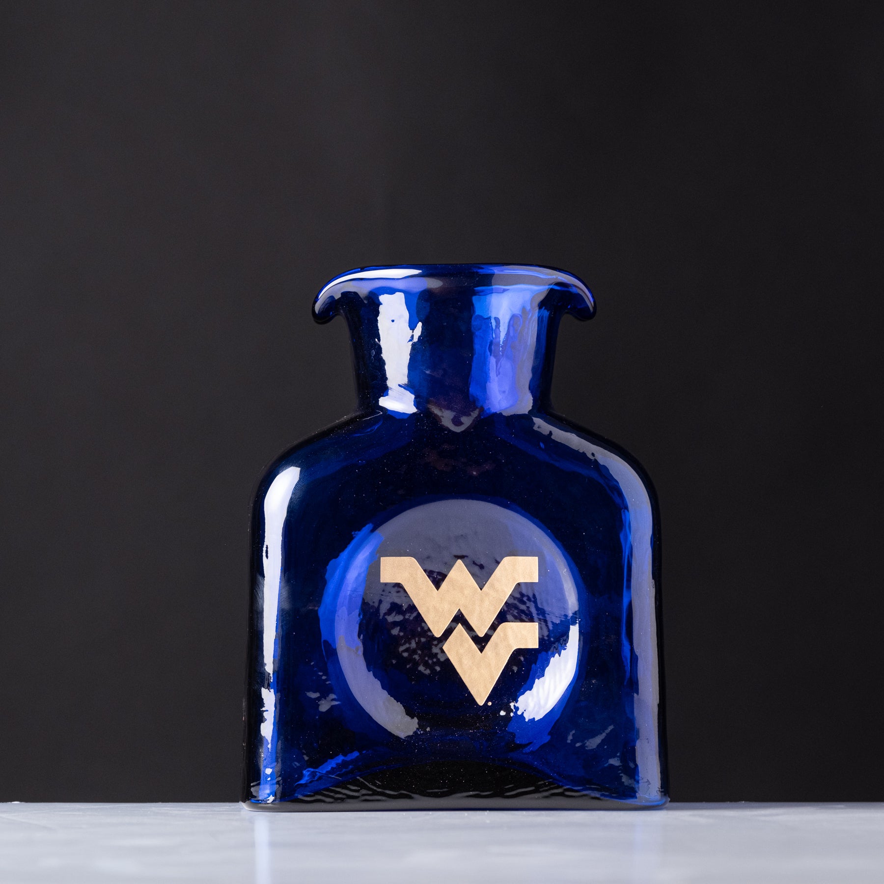 Blue glass bottle with a gold logo on a dark background