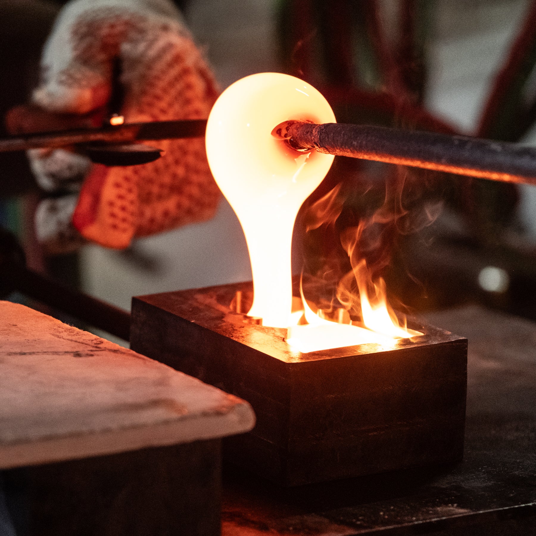 Glassblowing process with a glowing glass object being worked on.
