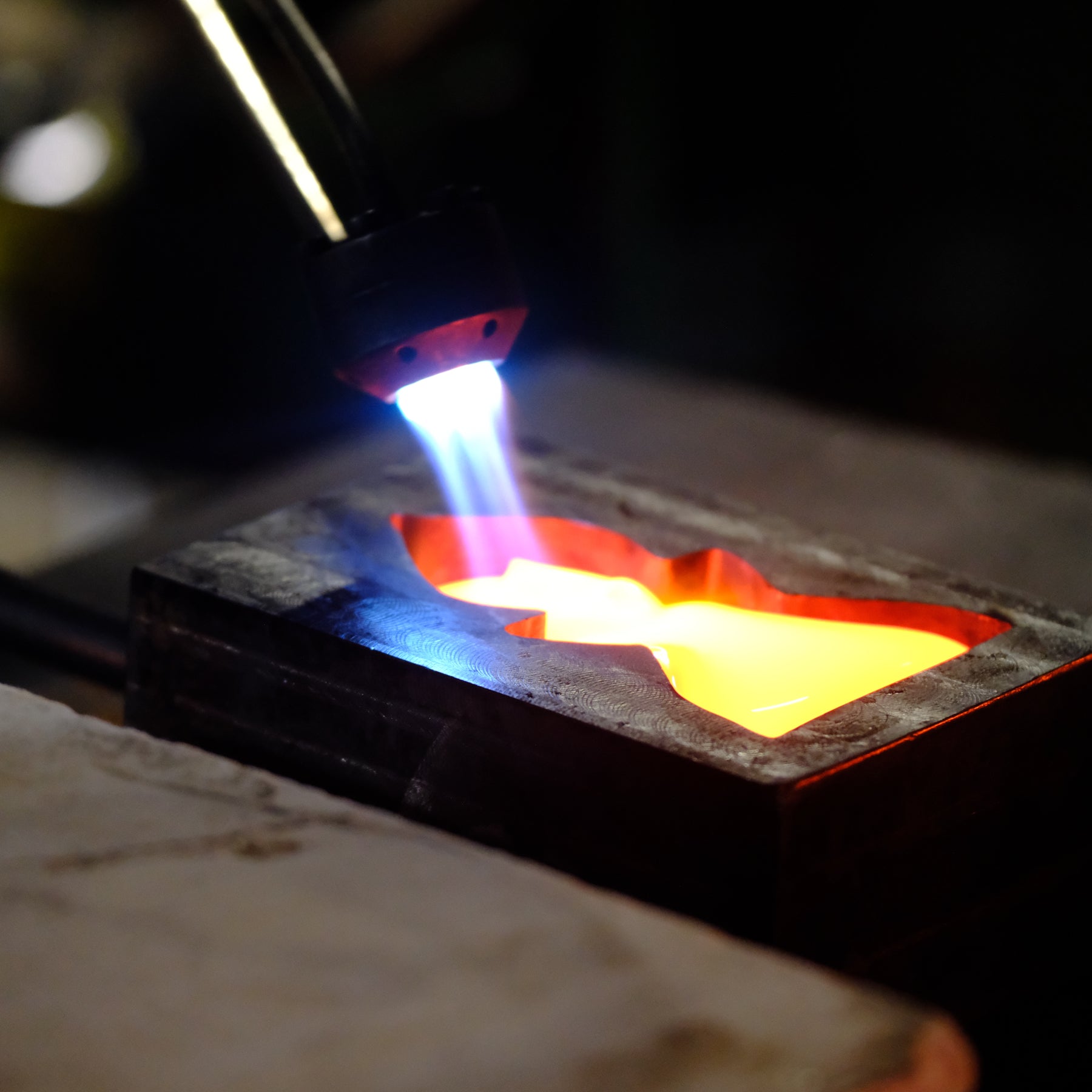 Flame from a torch interacting with a metal object on a dark background