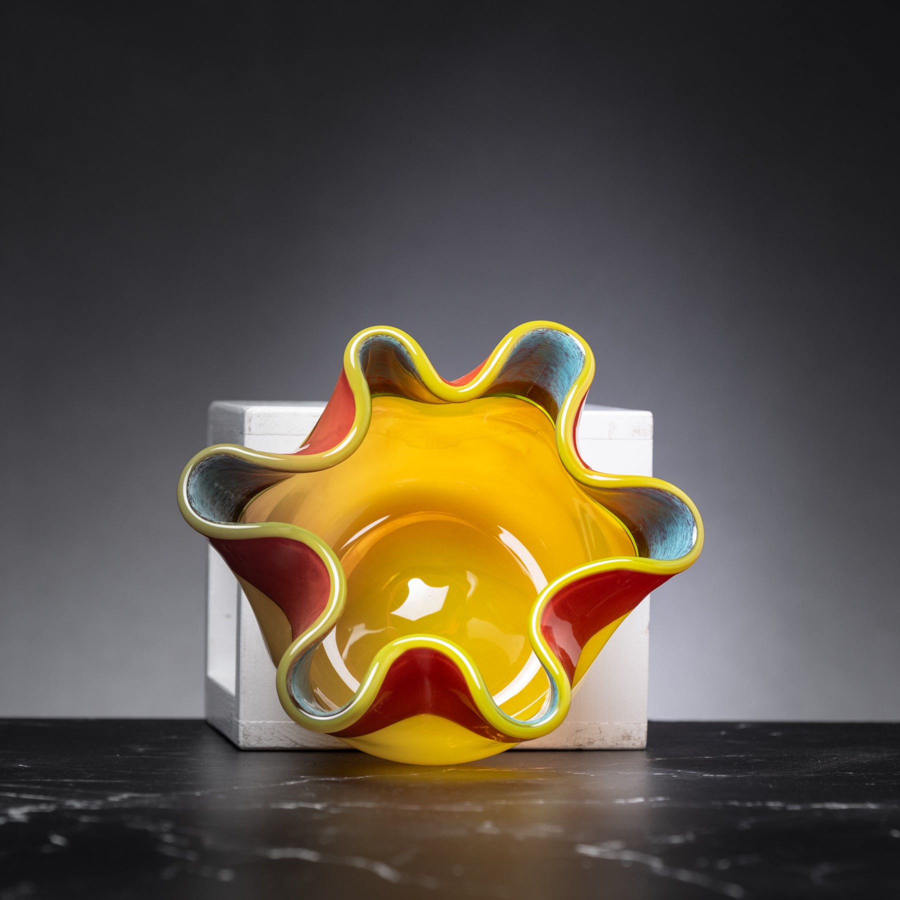 Colorful glass bowl on a dark surface with a gray background