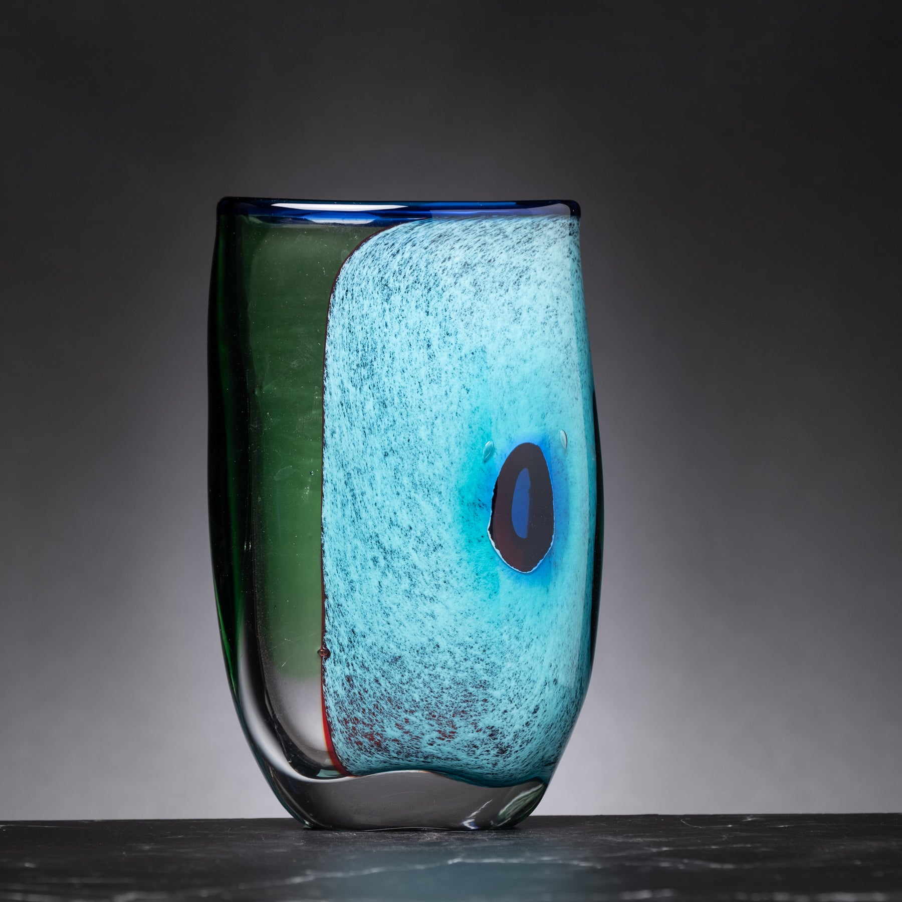 Glass vase with blue and green gradient on a dark background