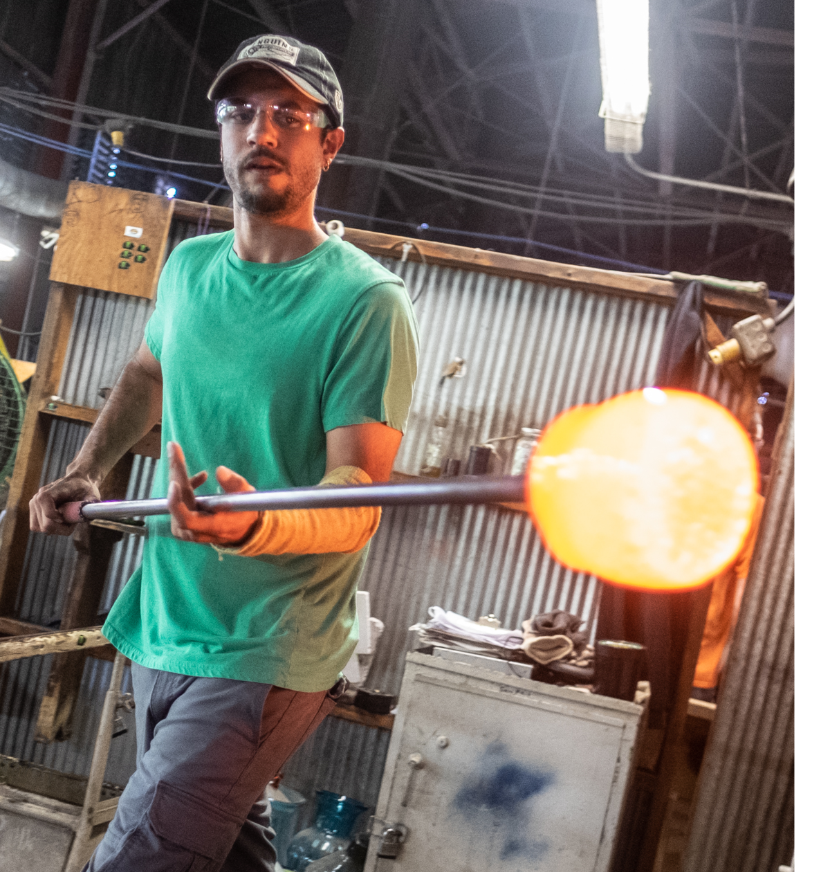 Person working with molten glass in a workshop setting