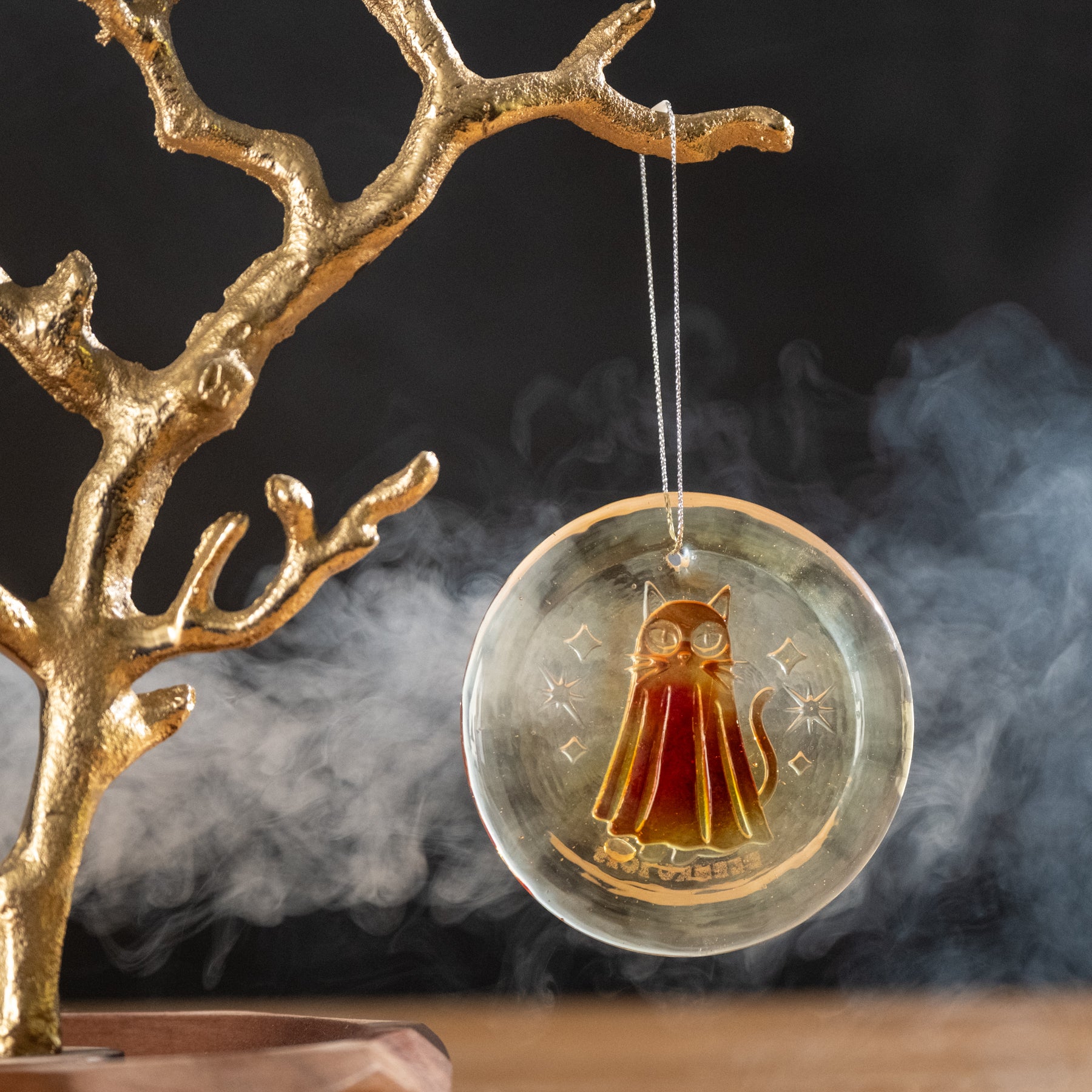 Decorative hanging ornament with a cat design on a dark background