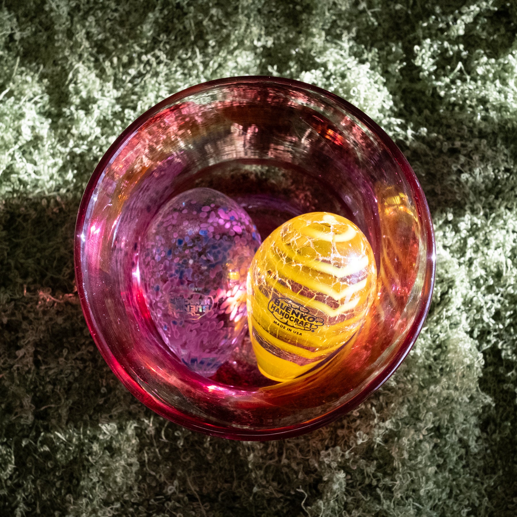 Pink glass bowl with a yellow object inside on a textured surface