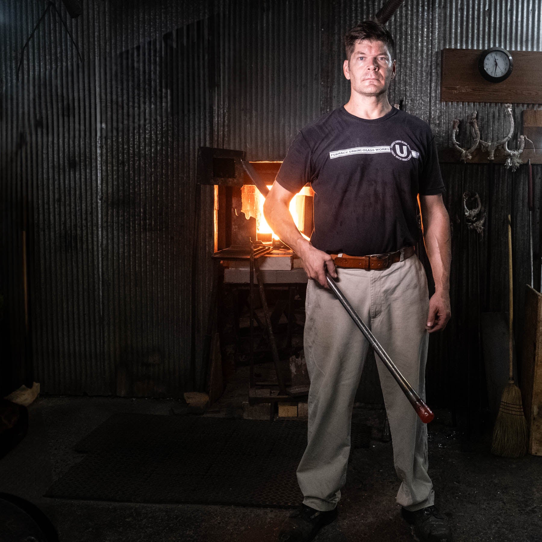 Man holding a blowpipe in a dimly lit room with rustic decor
