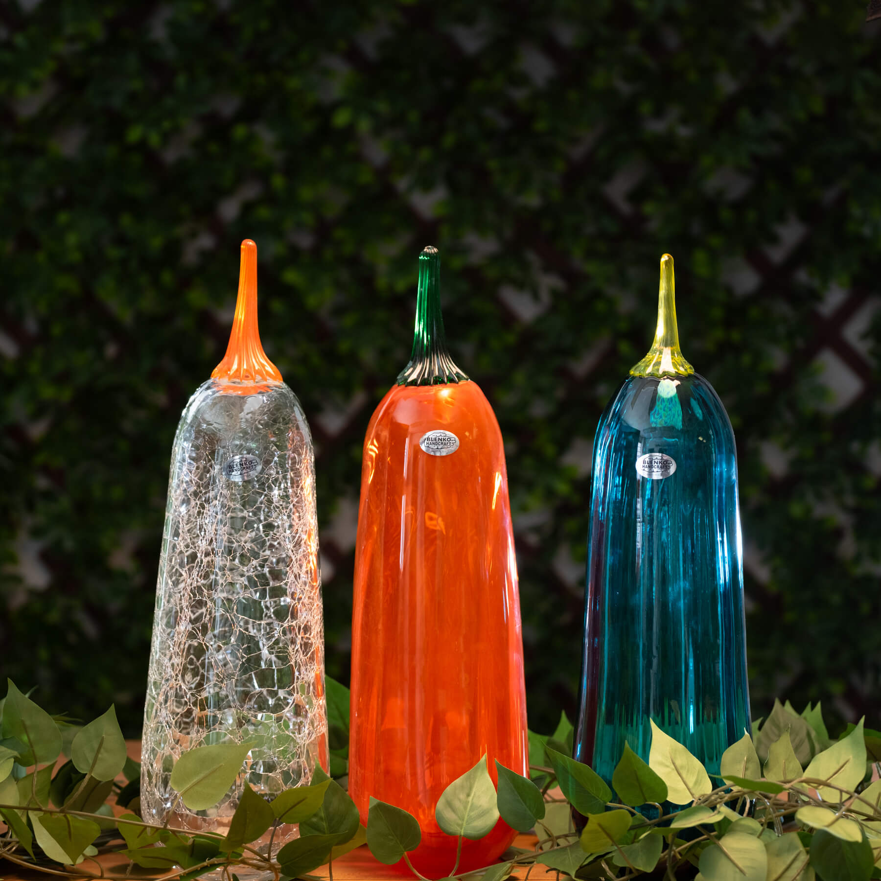 Three colorful glass tall pumpkins with on a leafy background