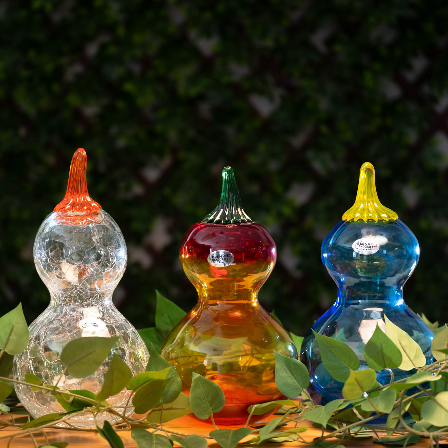 Three colorful glass gourds with leafy green background