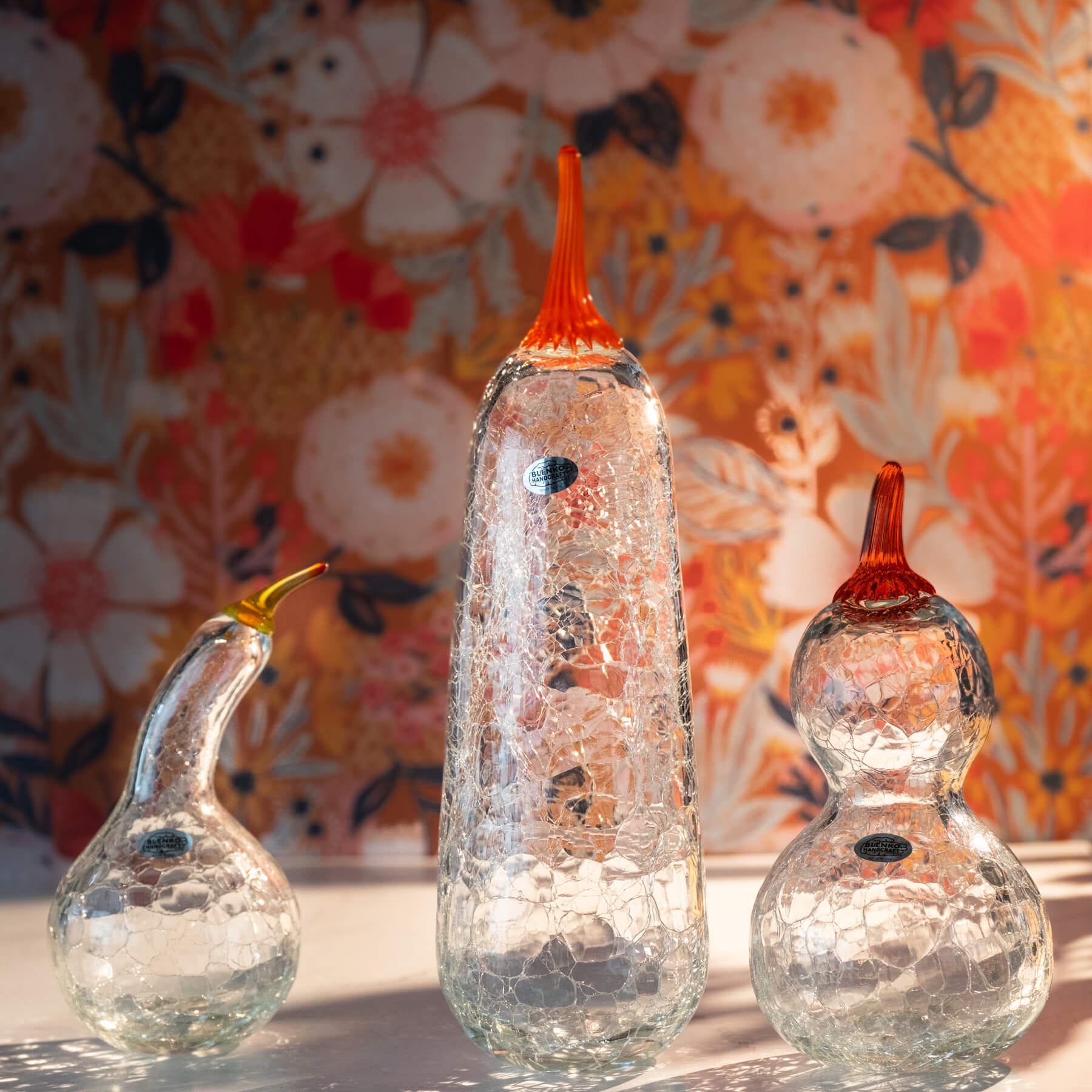 Three glass gourd-shaped pieces with cracked glass effect on a floral background