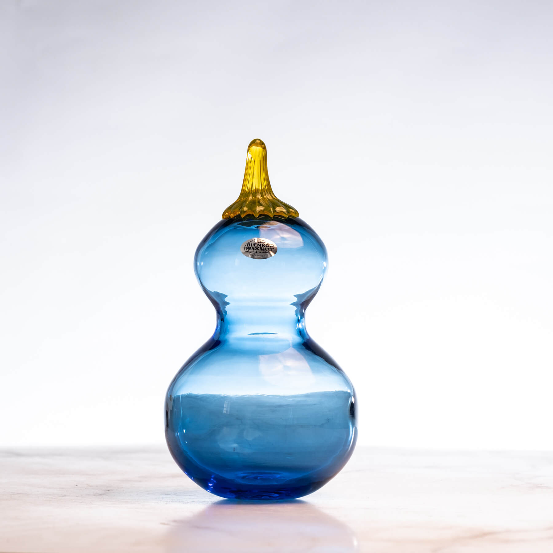 Blue glass calabash gourd a yellow stem on a white background