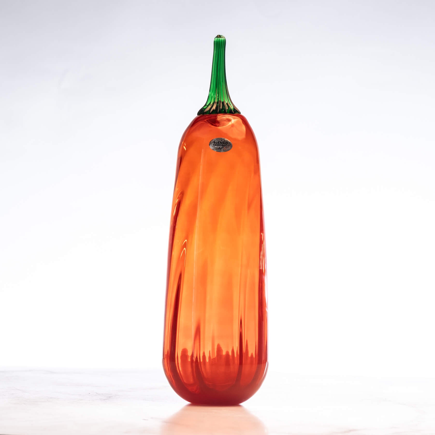 Orange glass gourd with green stem on a white background