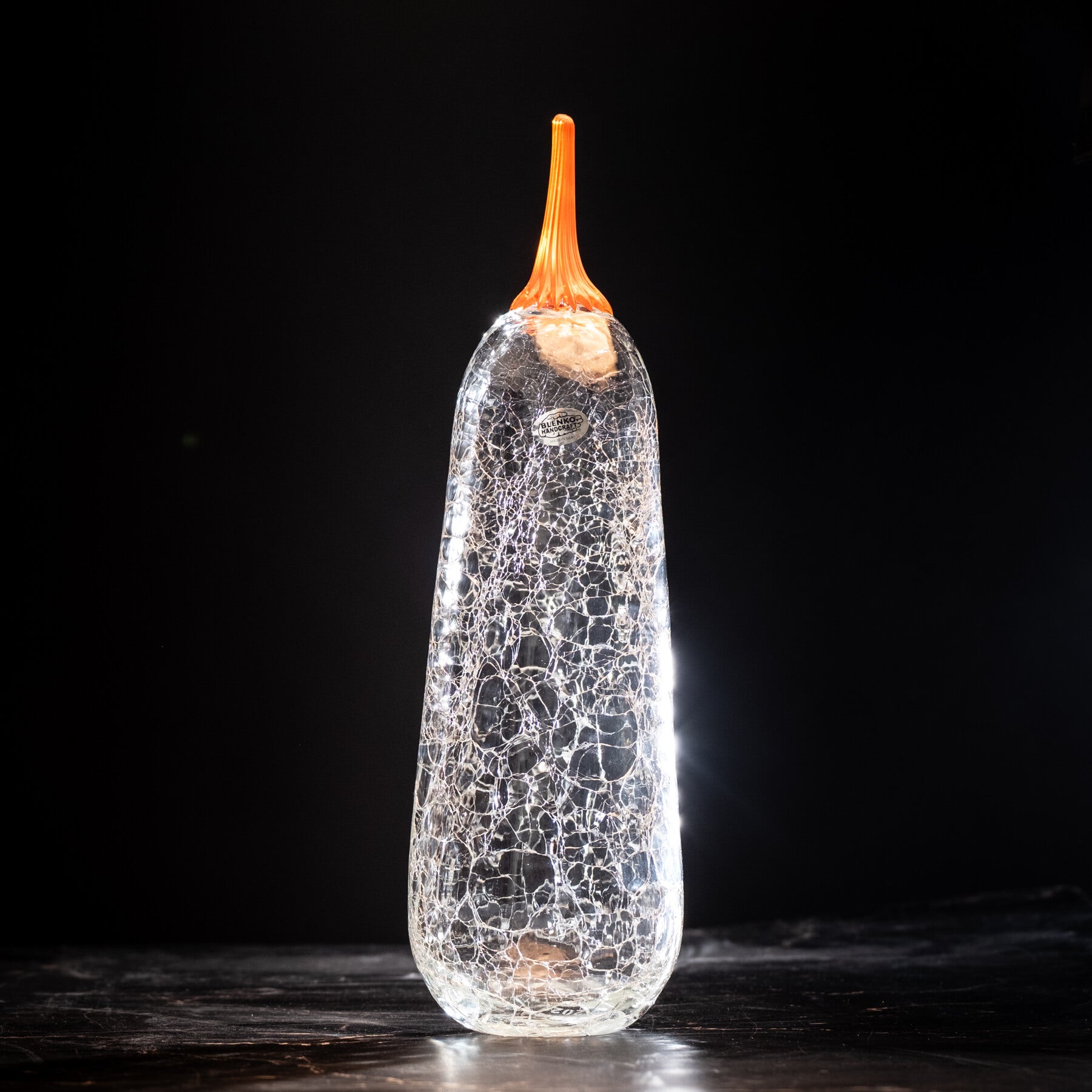 Crackle crystal glass pumpkin with an orange stem on a dark background
