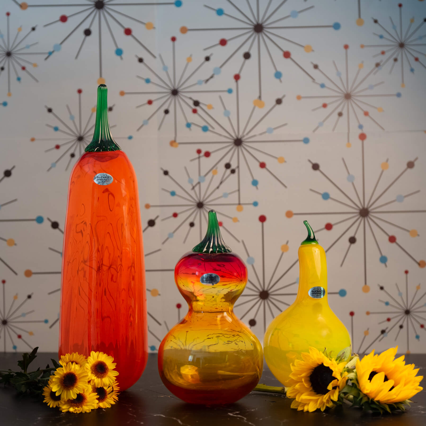 Three colorful glass gourds with sunflowers on a decorative background