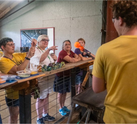 Glassworker showing guests a molten ball of glass on a blowpipe