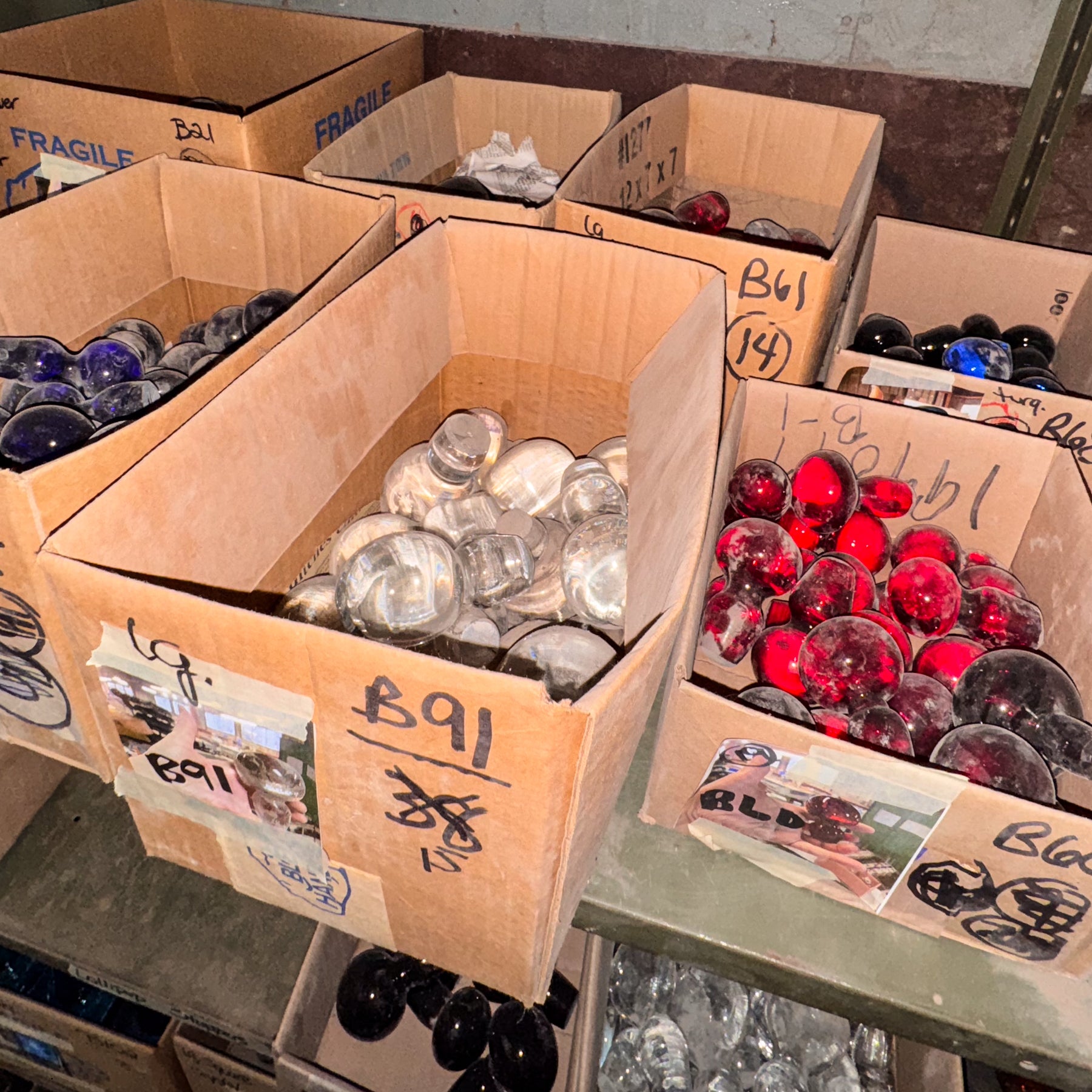 Cardboard boxes containing various glass items on a concrete floor.