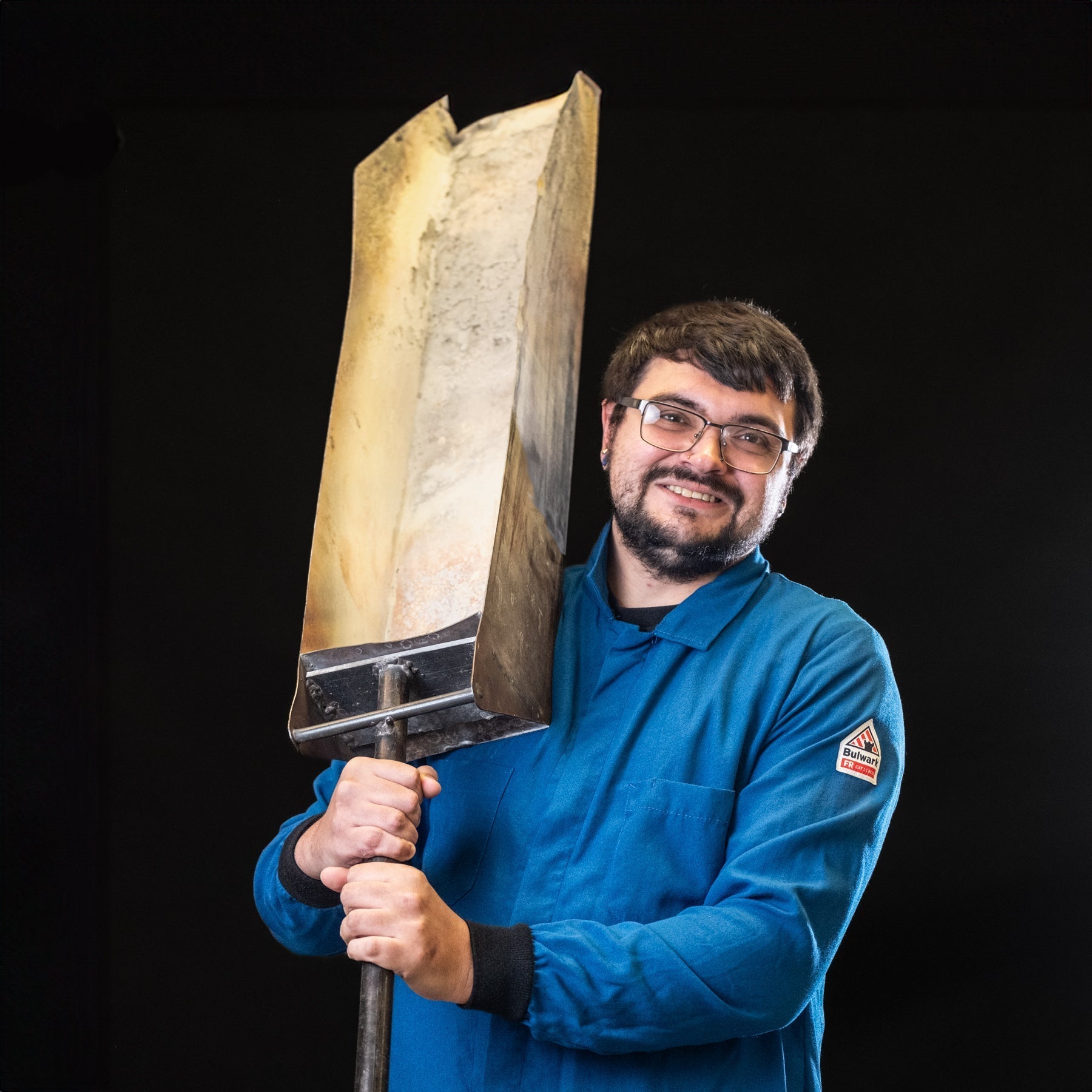 Person holding a large hammer against a black background