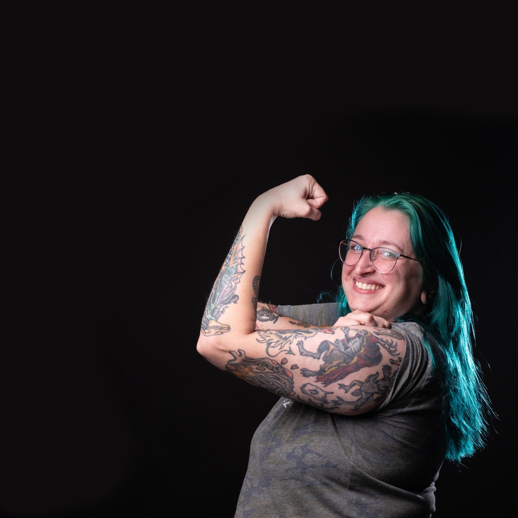Person with tattoos flexing their arm against a black background