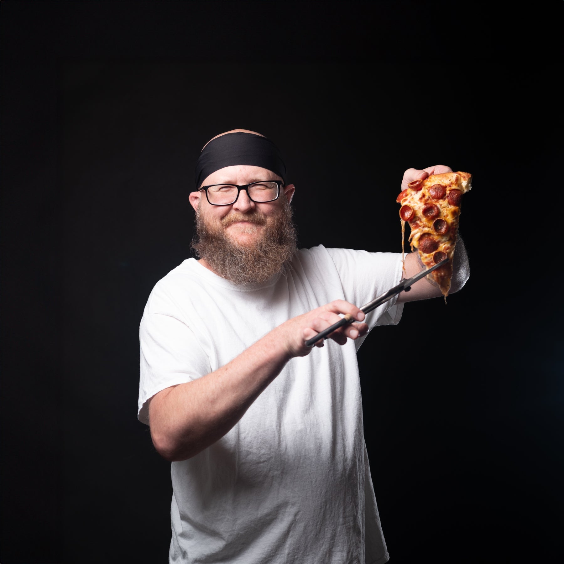 Man holding a slice of pizza against a black background