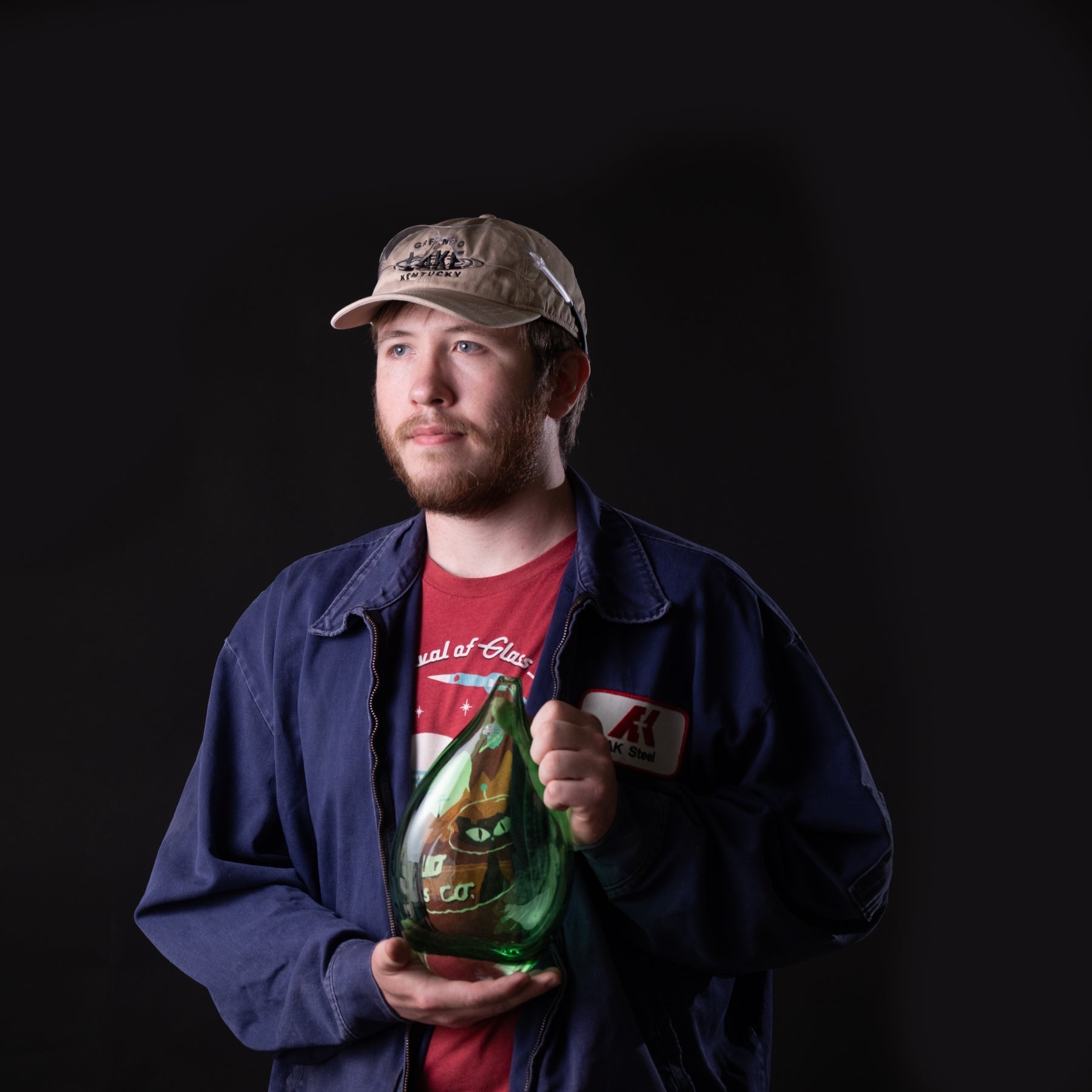 Man holding a green vase against a black background