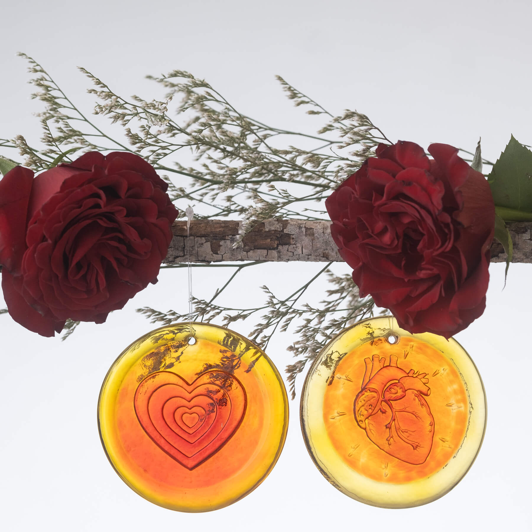 2 Heart' Suncatcher in Tangerine hanging one a stick with 2 roses.