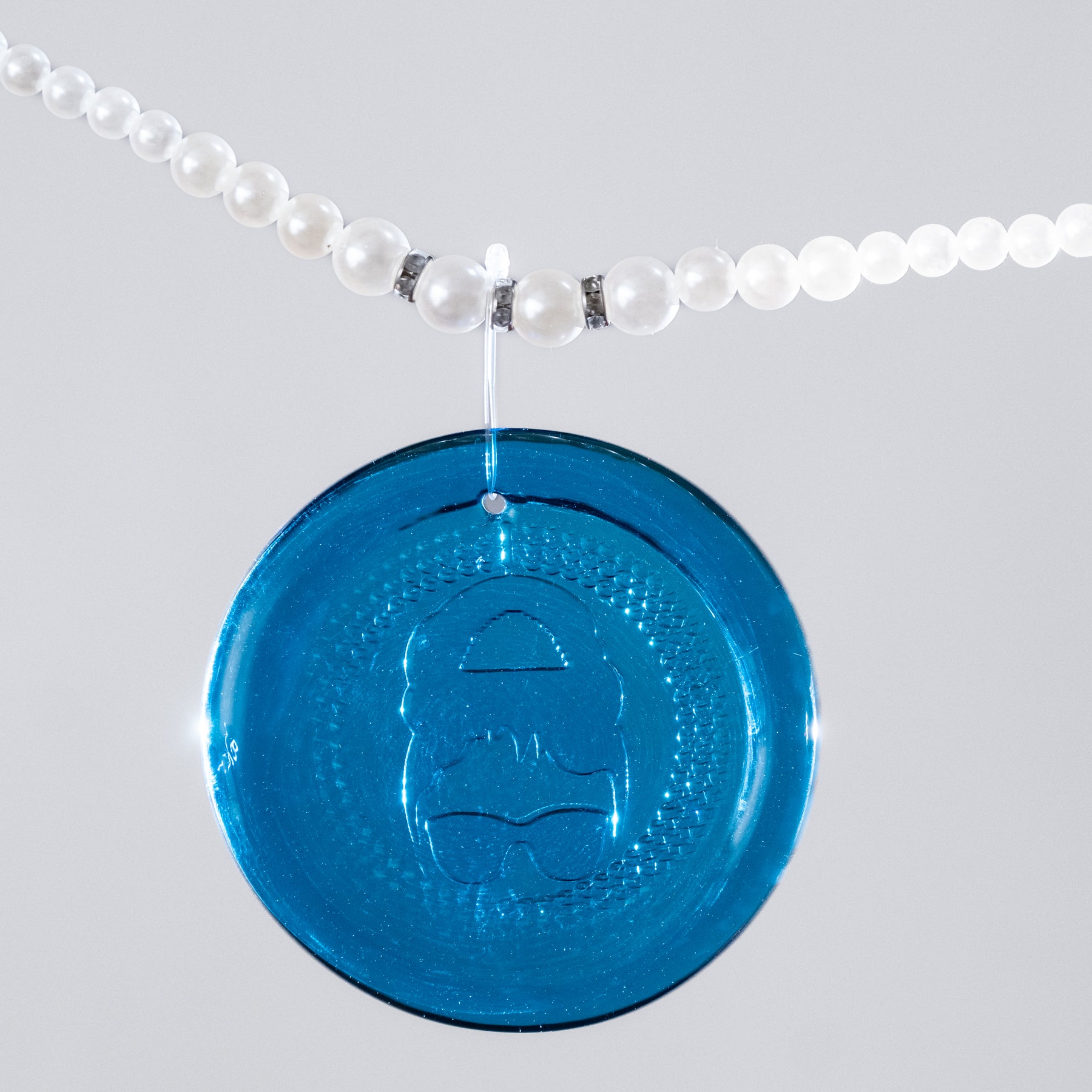 Turquoise Suncatcher on a pearl necklace with white background