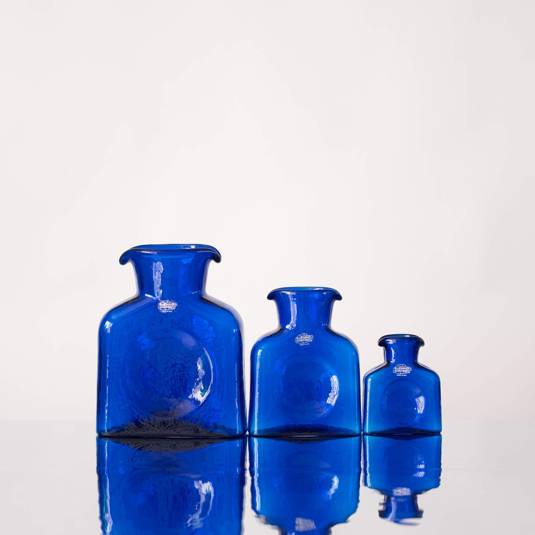 Three blue glass vases of different sizes on a white background